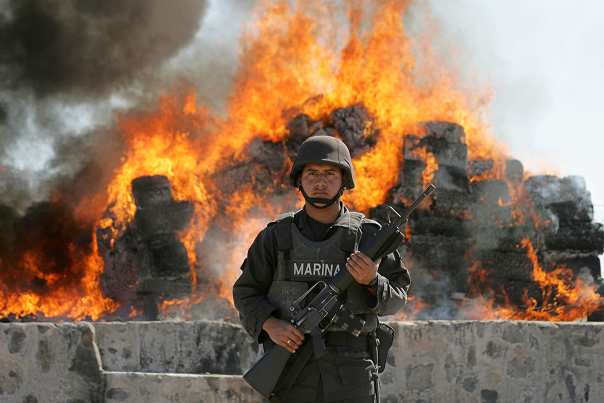 A Mexican marine stands in front of a burning pile of cocaine at a naval base in Sinaloa, Mexico, in January 2007. Daniel Aguilar/Reuters