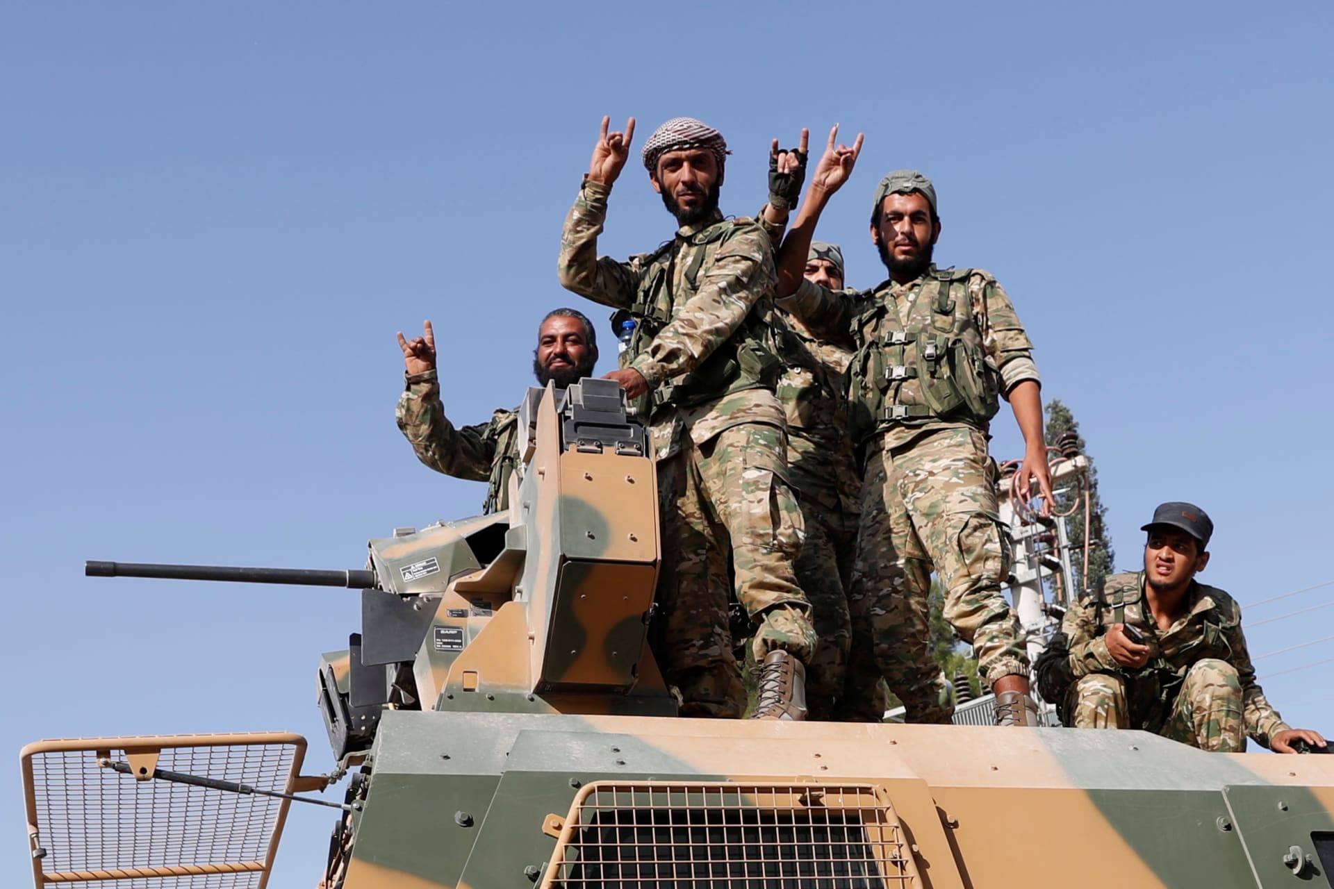 <p>Members of the Syrian National Army on top of an armored vehicle in Ceylanpinar, Turkey.</p>