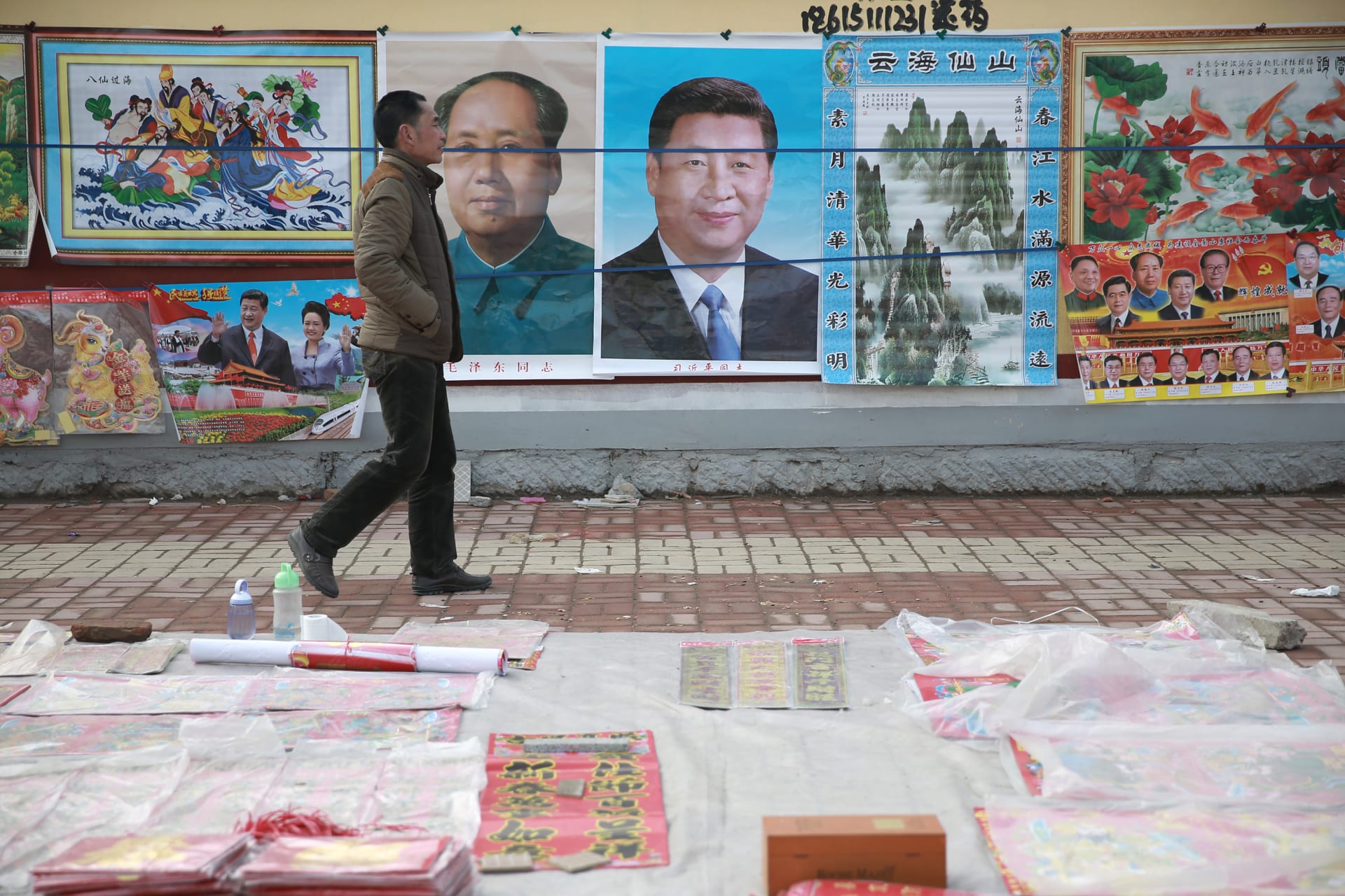 <p>A man walks past New Year decoration pictures featuring China’s President Xi Jinping, China’s late Chairman Mao Zedong and some other current senior officials, at a market in Juancheng, Shandong province, February 17, 2015. The Chinese Lunar New Year on F</p>