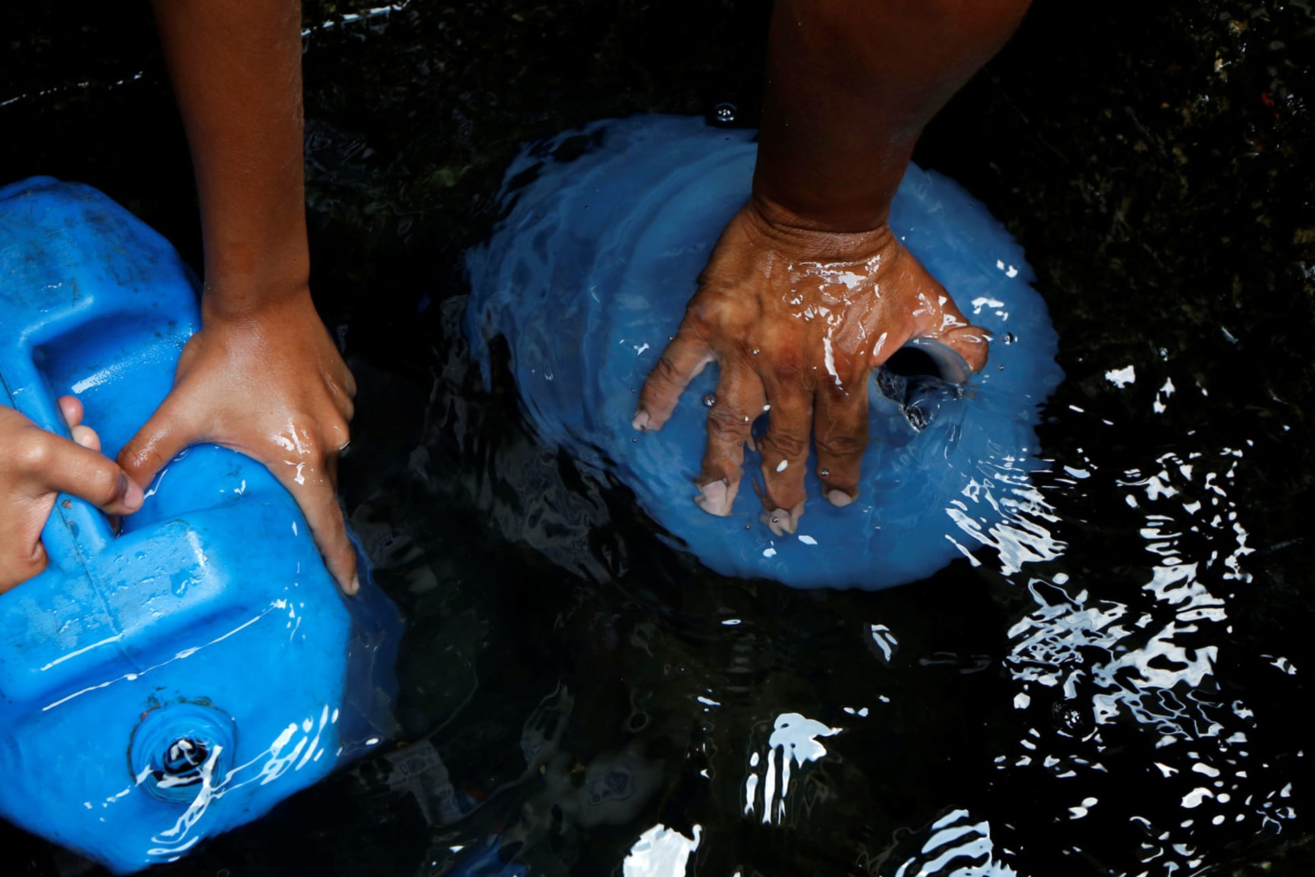 <p>People fill plastic containers with water in a well on the street, close to a neighbourhood called “The Tank” at the slum of Petare in Caracas, Venezuela, April 3, 2016.</p>
