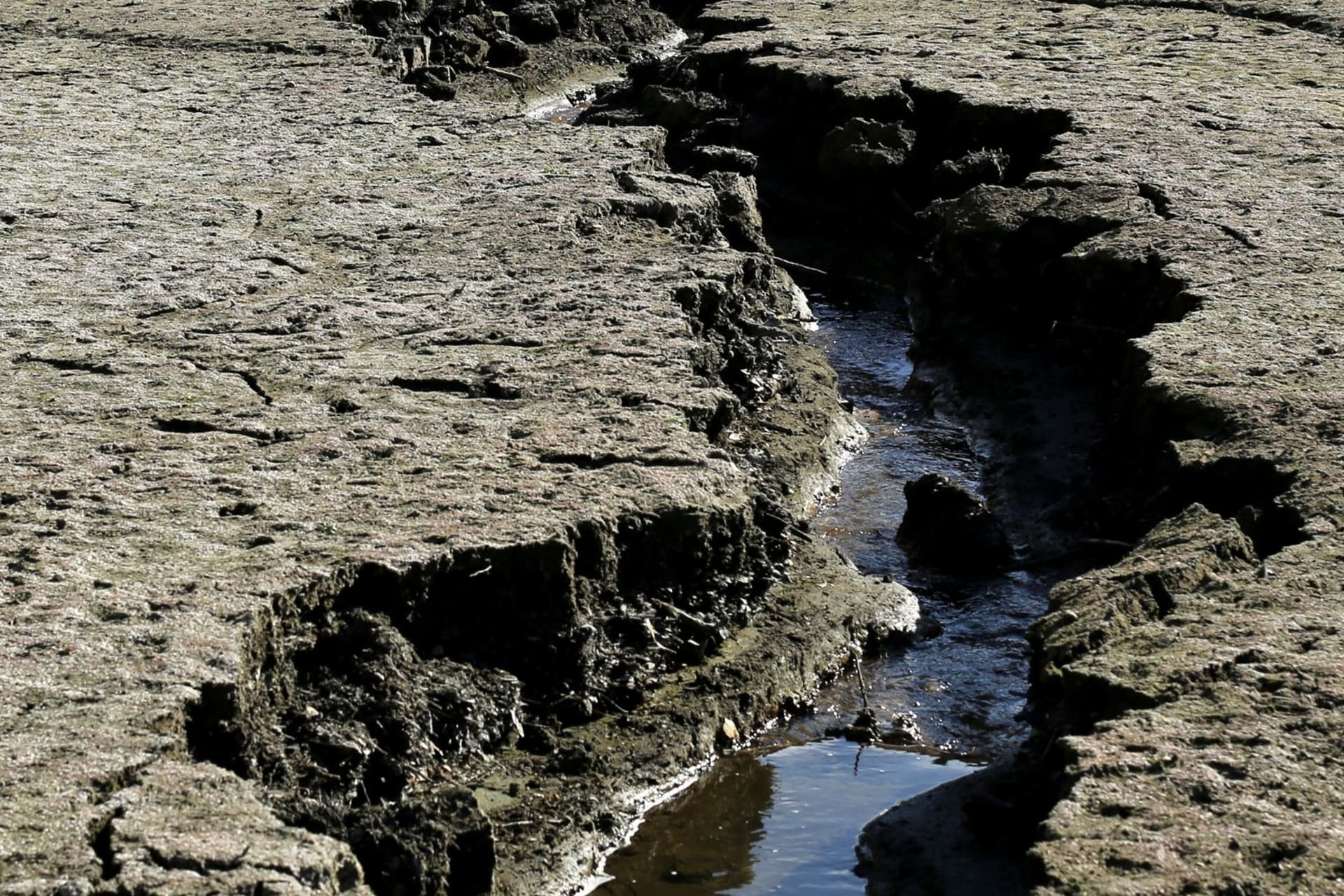 <p>A stream of water trickles on the bottom of the Almaden Reservoir near San Jose, California during a statewide drought emergency in 2014.</p>
