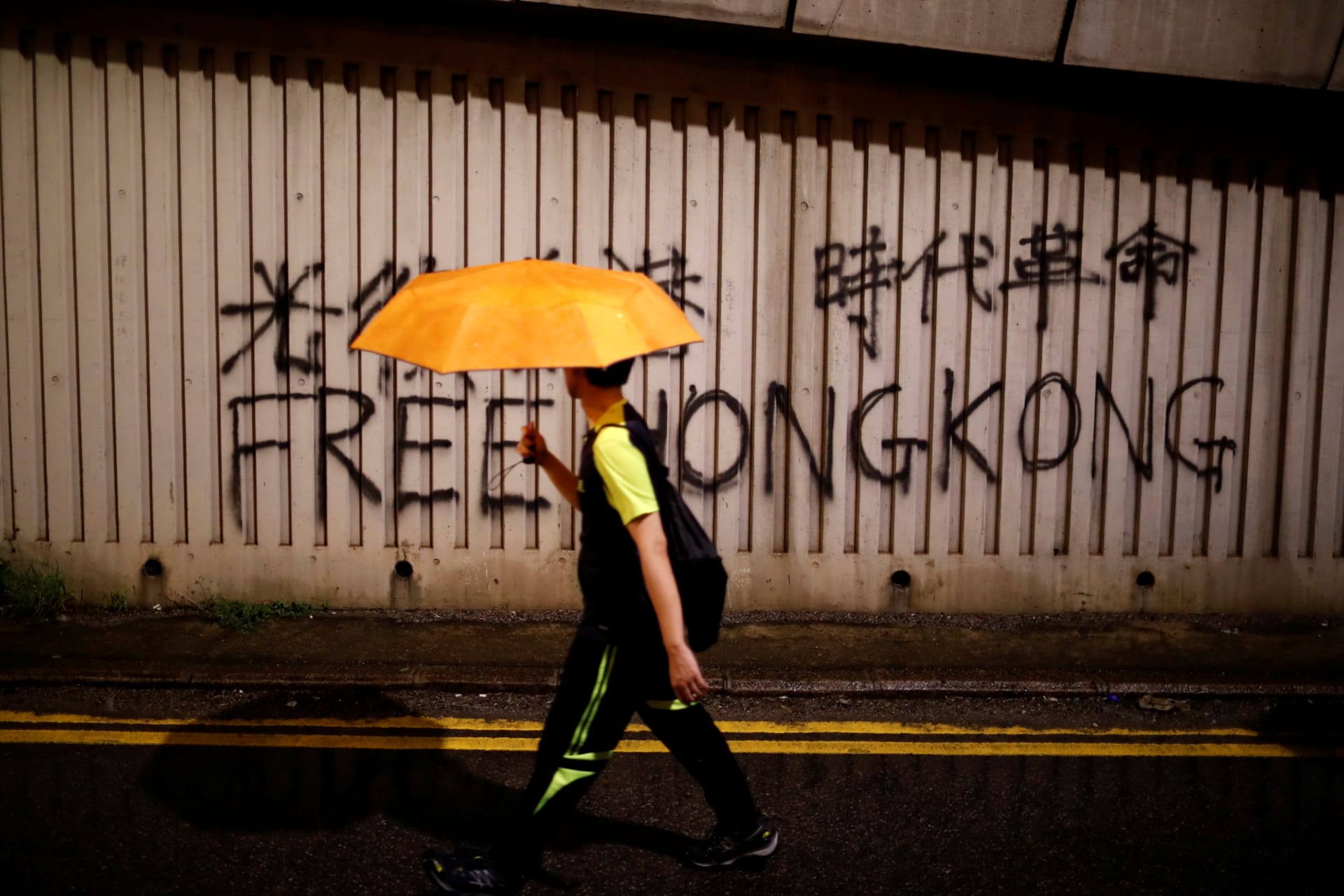 <p>A man walks past a graffiti during a march to demand democracy and political reforms in Hong Kong, China, August 18, 2019.</p>
