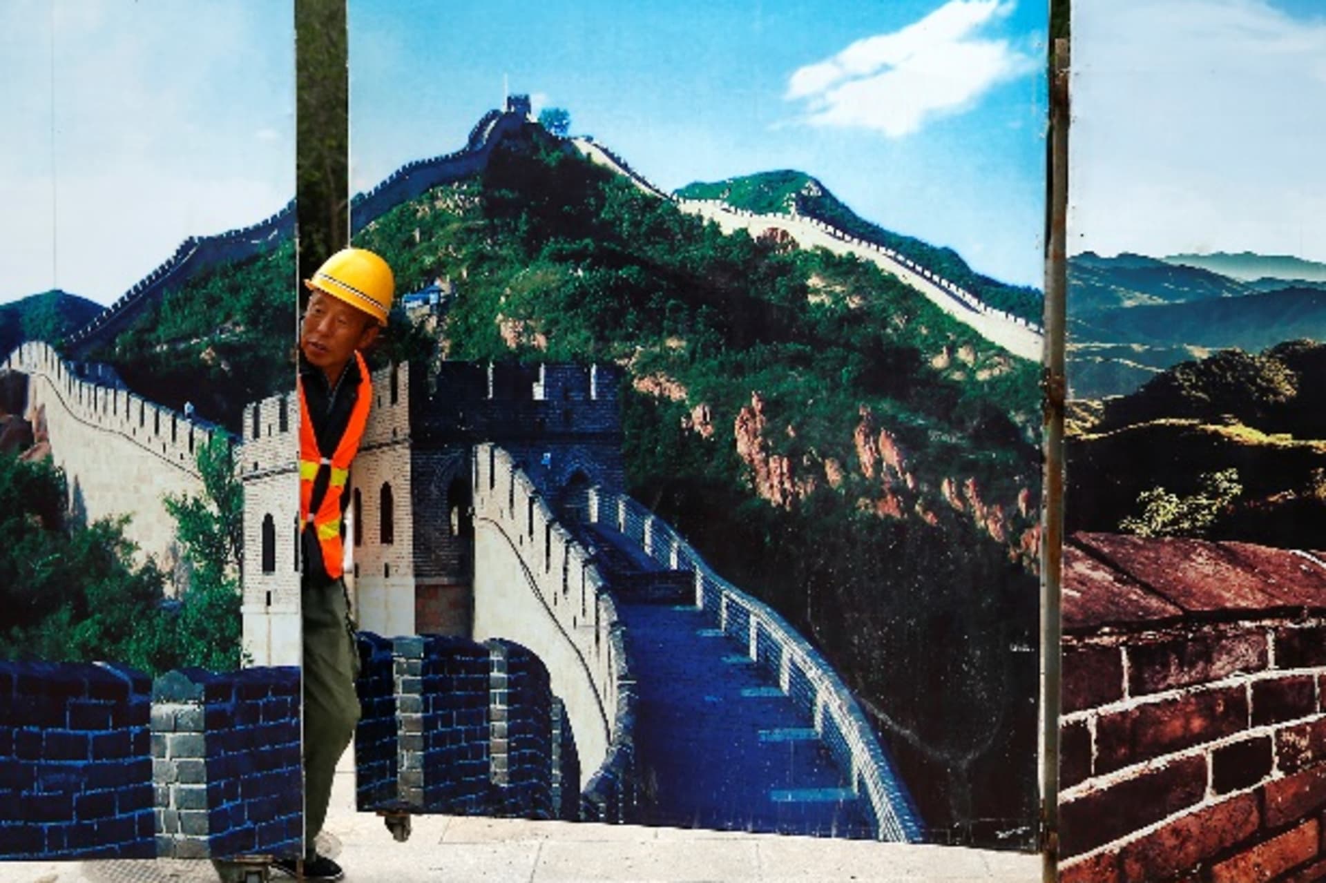 <p>A worker looks through the fence of a construction site that is decorated with pictures of the Great Wall at Badaling, north of Beijing, China, September 1, 2016. REUTERS/Thomas Peter</p>
