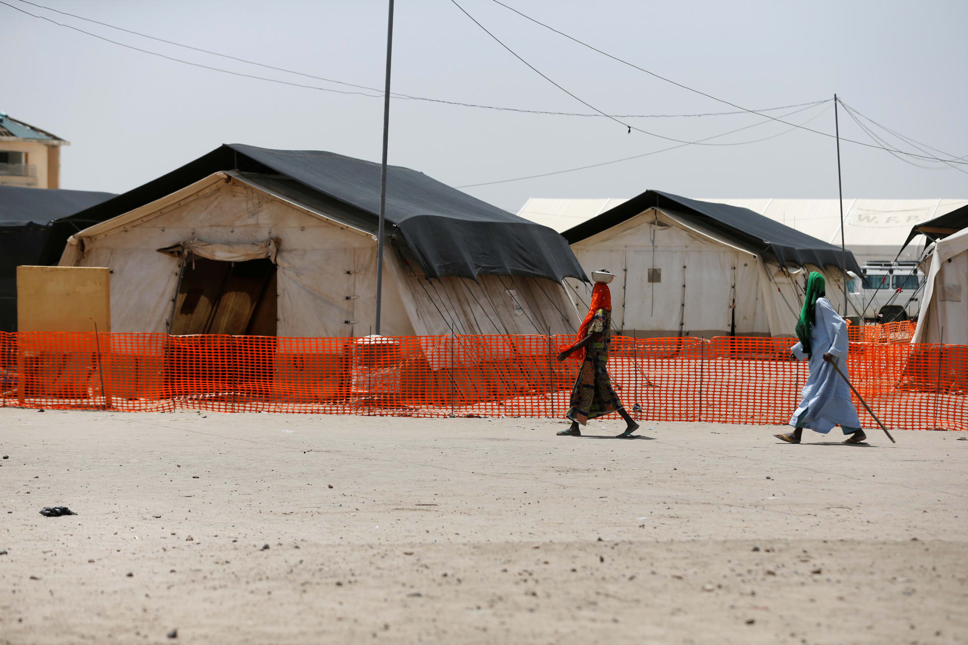 <p>A man and a woman walk past the World Food Program (WFP) tents at the Banki IDP camp, Borno, Nigeria, April 27, 2017.</p>
