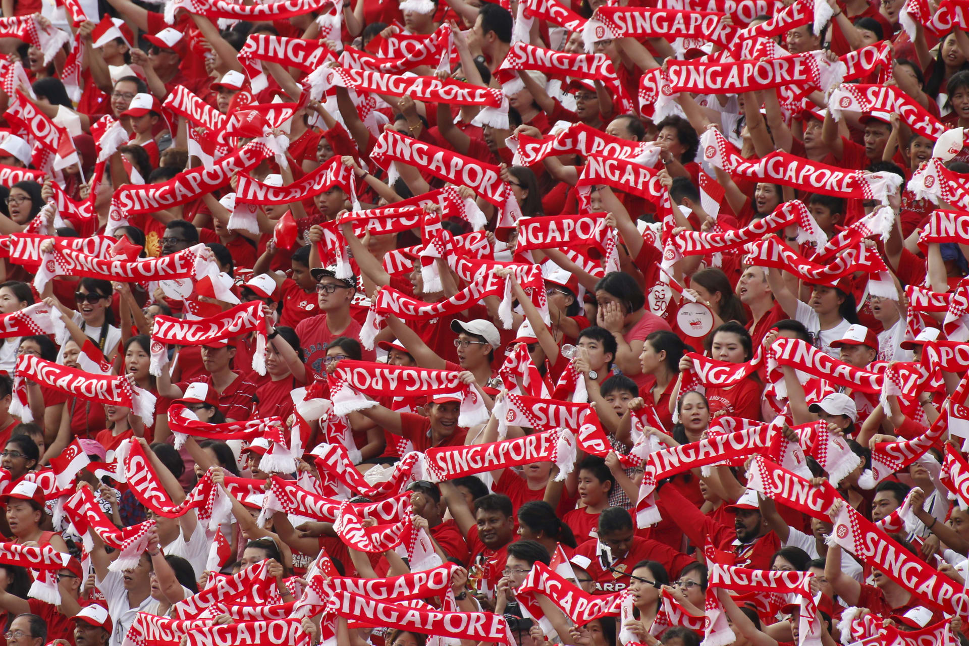 <p>People hold up Singapore banners during Singapore’s Golden Jubilee celebration parade for the nation’s 50th anniversary at Padang near the central business district on August 9, 2015.</p>
