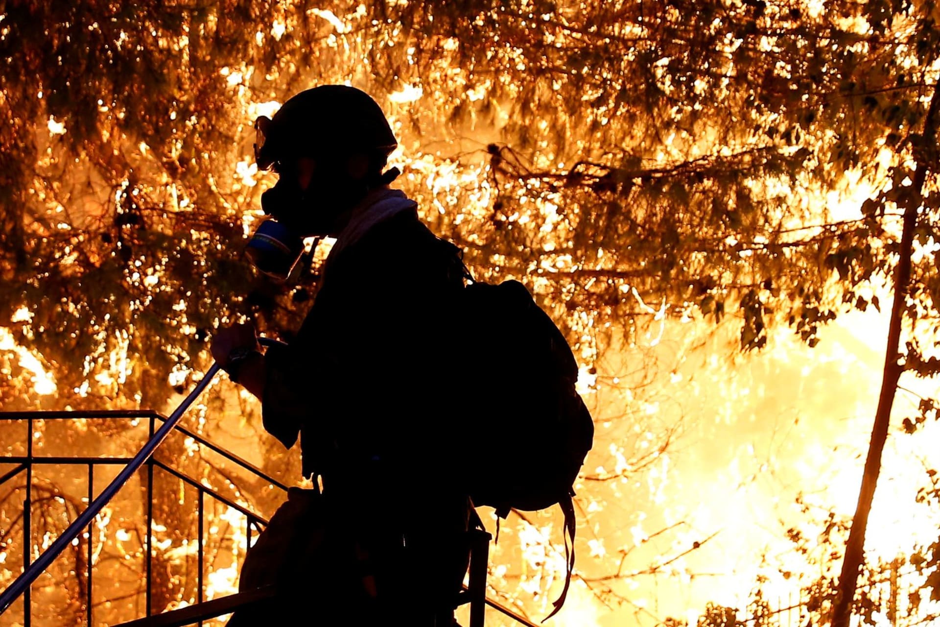 <p>A volunteer sprays water as a wildfire burns near Athens, Greece. </p>