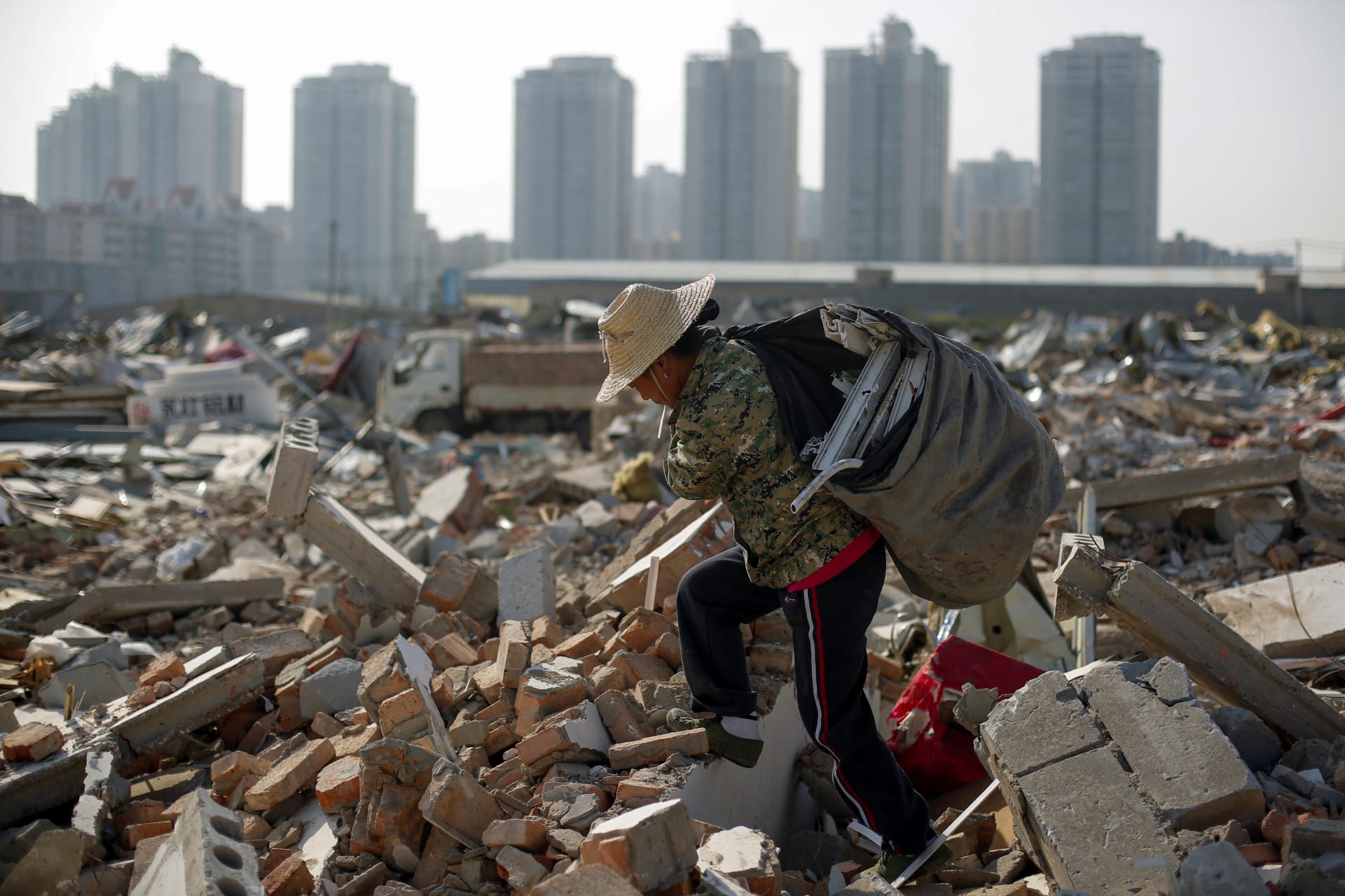 <p>Migrant worker Wang Jun carries scrap material she collected from debris of demolished buildings at the outskirts of Beijing, China October 1, 2017. </p>
