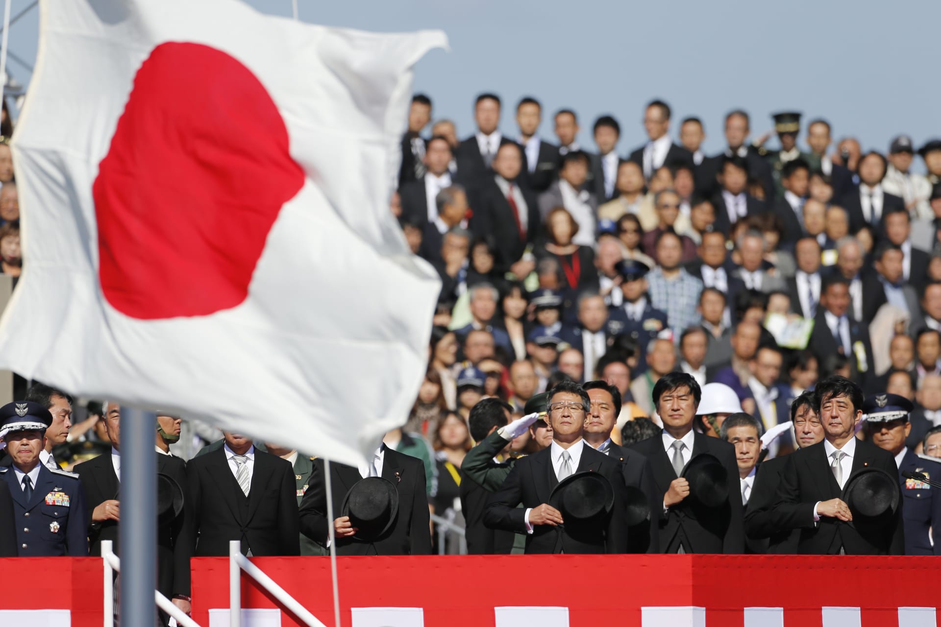 Japanese Prime Minister Shinzo Abe salutes Japan's national flag as he reviews Japan Self-Defence Forces troops during an annual ceremony at Asaka Base in Asaka on October 27, 2013.