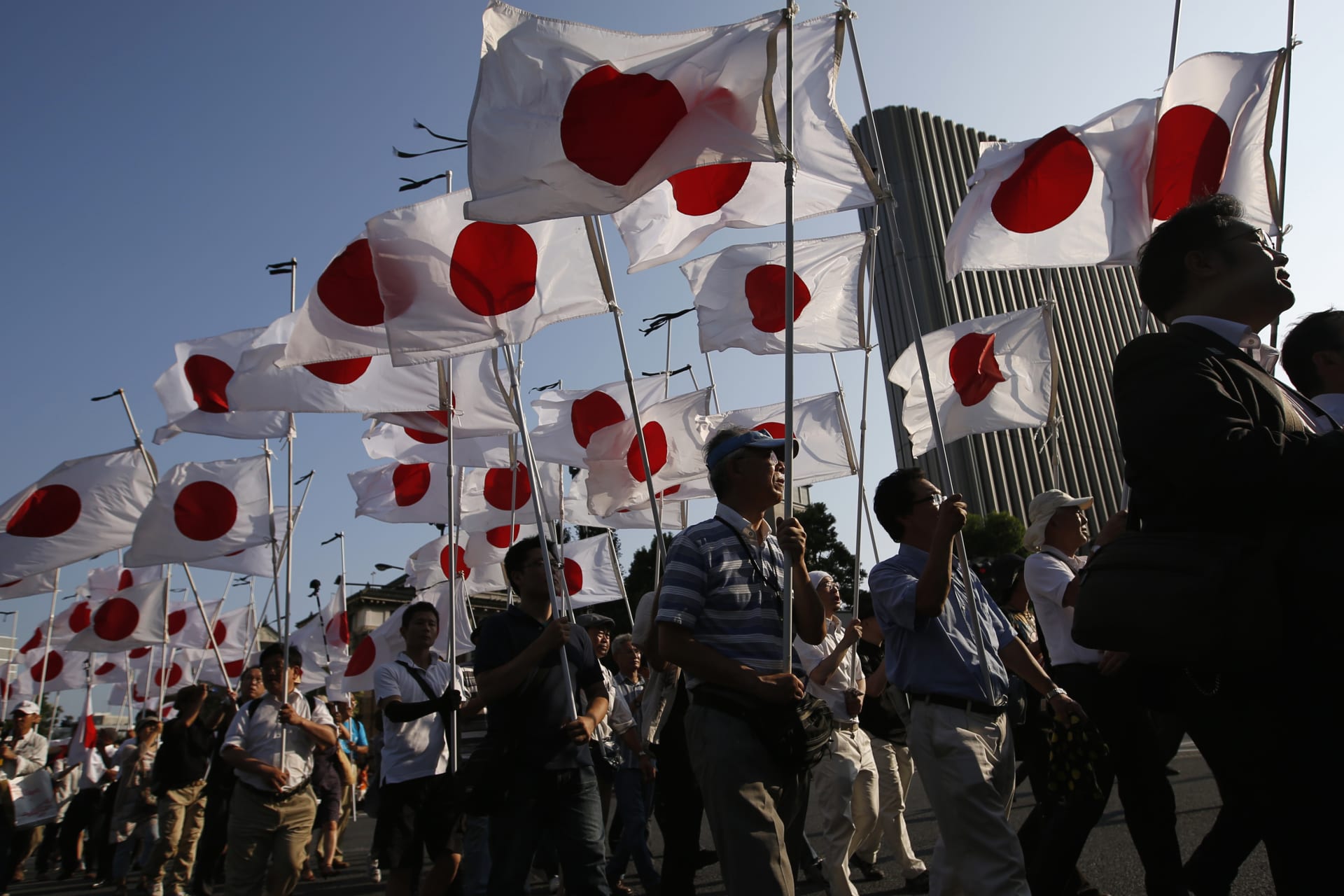 Members of the nationalist movement "Ganbare Nippon" march with Japanese national flags while paying tribute to the war dead near Yasukuni Shrine in Tokyo August 15, 2013.