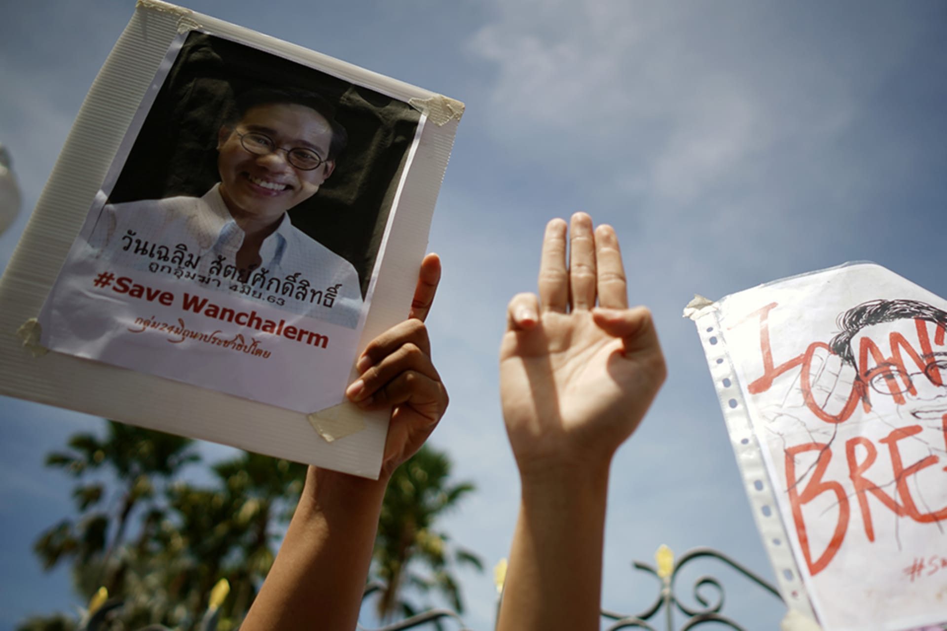 <p>Activists hold up pictures of abducted Thai activist Wanchalearm Satsaksit and flash a three fingers salute as people gather in support of him during a protest calling for an investigation, in Bangkok, Thailand, on June 12, 2020</p>
