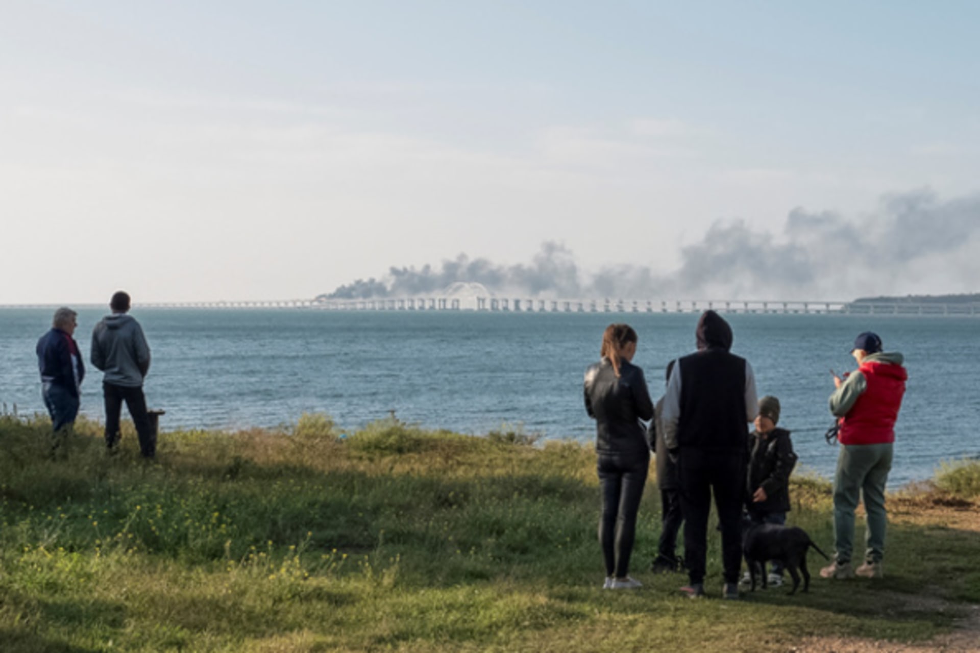<p>People watch fuel tanks ablaze and damaged sections of the Kerch bridge in the Kerch Strait, Crimea.</p>
