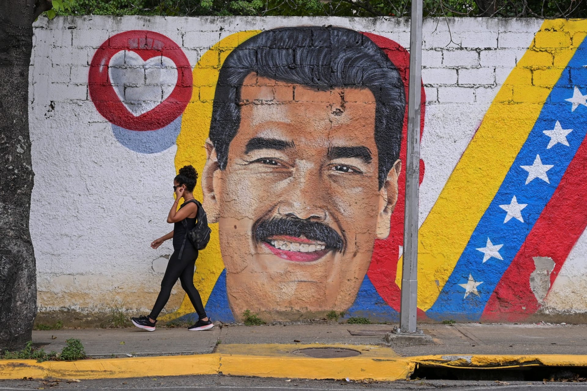 A woman walks past a mural of Venezuela's President Nicolas Maduro