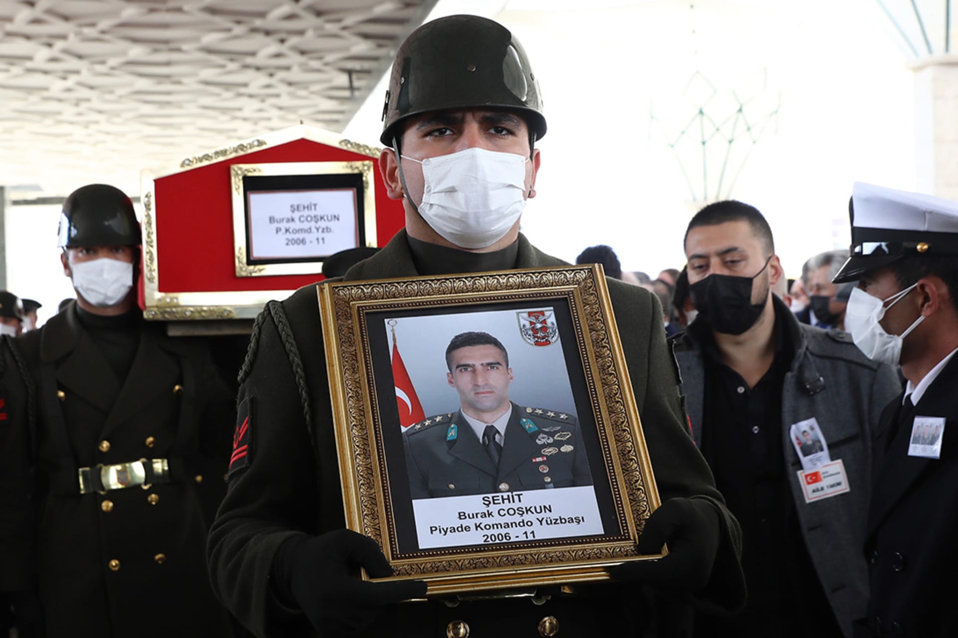 An officer holds an image of Lieutenant Burak Coskun during funeral prayers for three Turkish military personnel killed in action. 