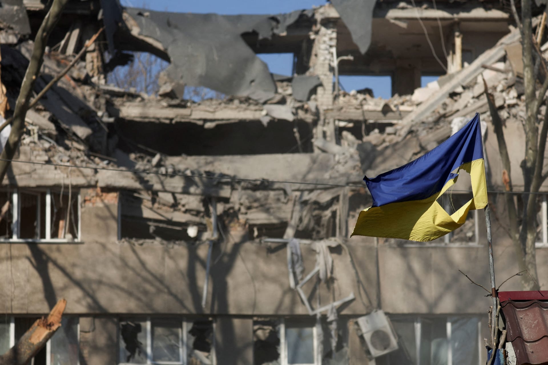 <p>A Ukrainian flag waves in front of a damaged building hit in a military strike, as Russia’s invasion of Ukraine continues, in Mykolaiv, Ukraine, March 21, 2022</p>
