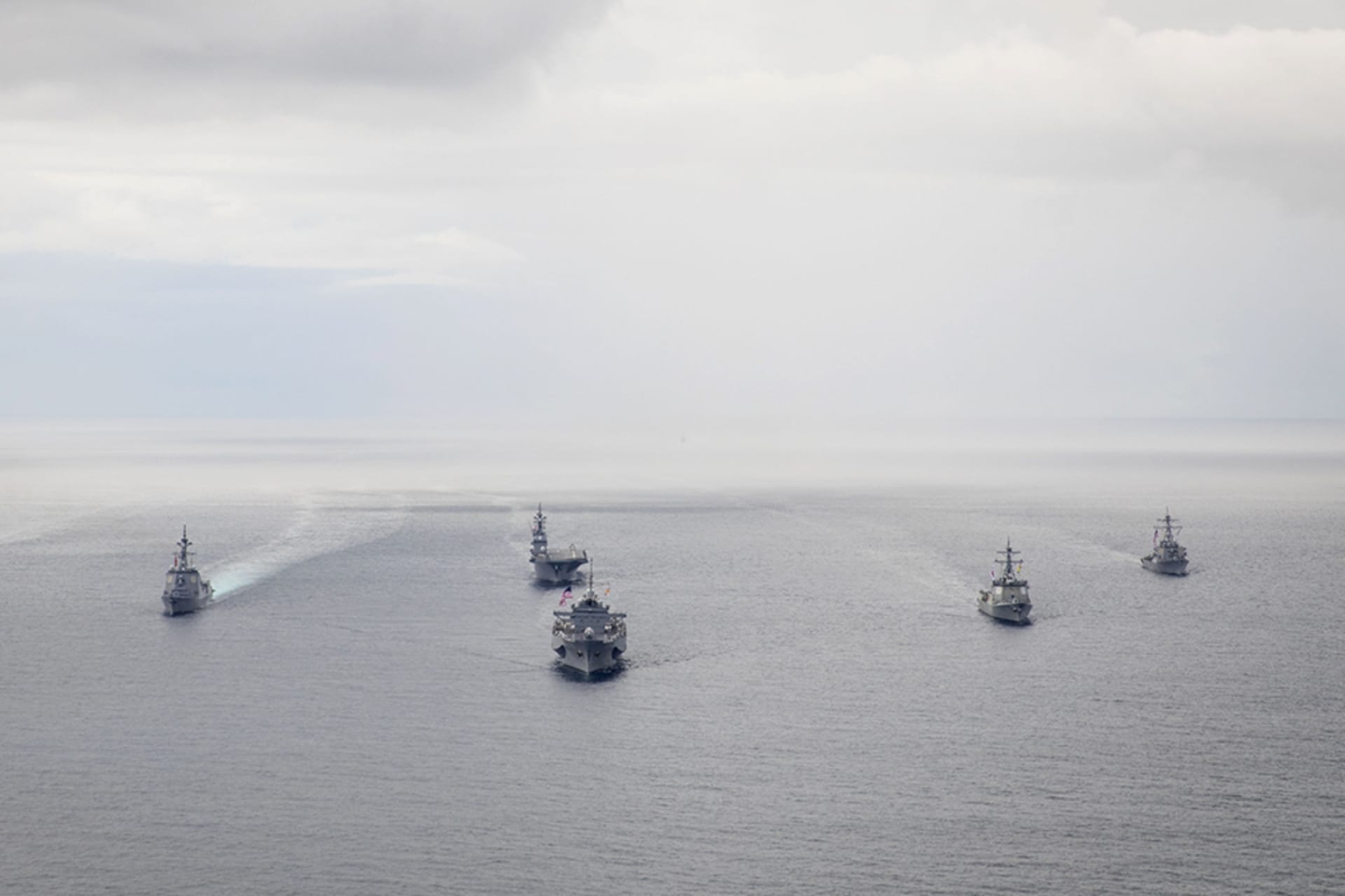Several U.S. naval vessels cruising on open water.