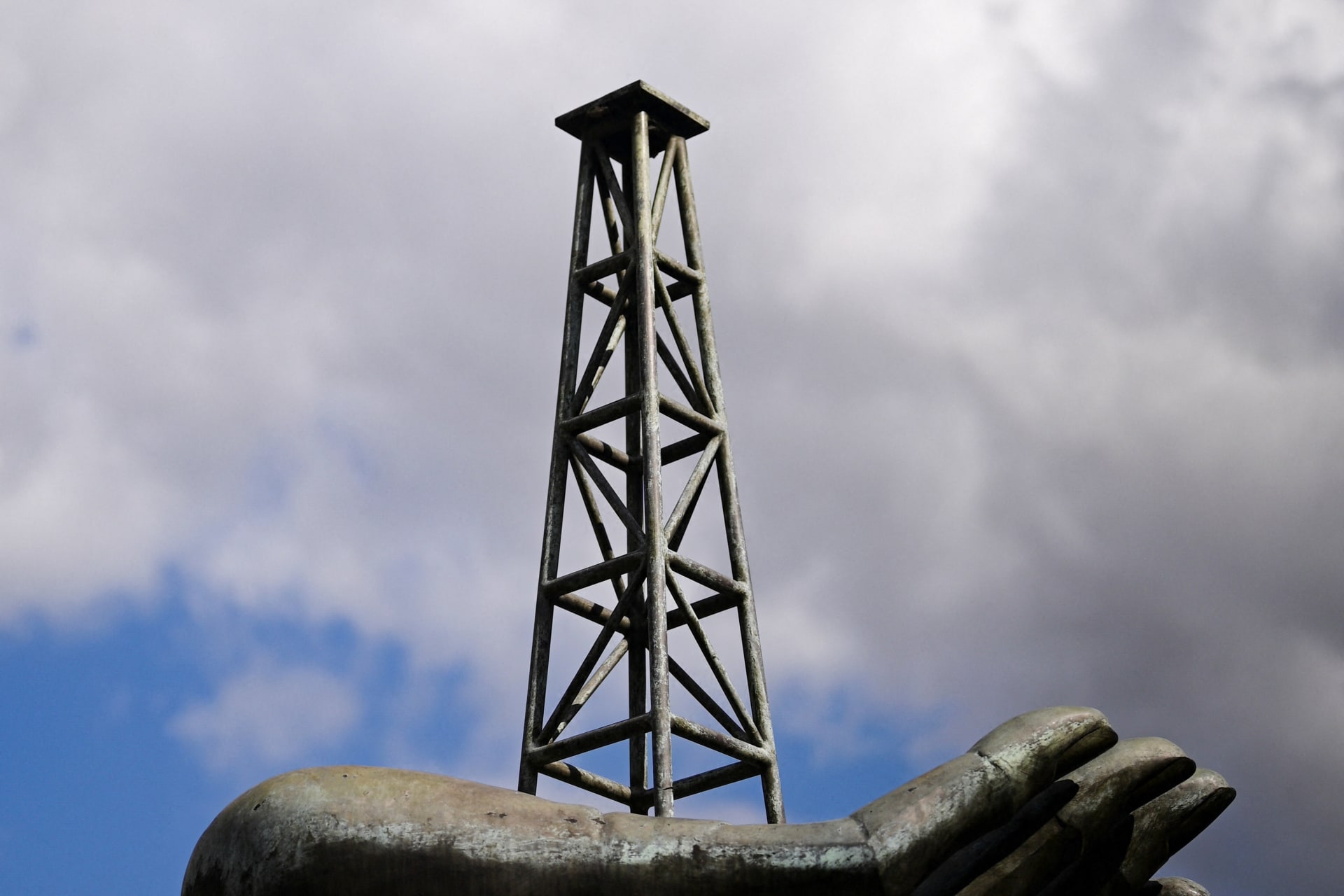 A structure of a hand holding an oil well tower stands near the headquarters of Venezuela's state-run oil company PDVSA, in Caraca