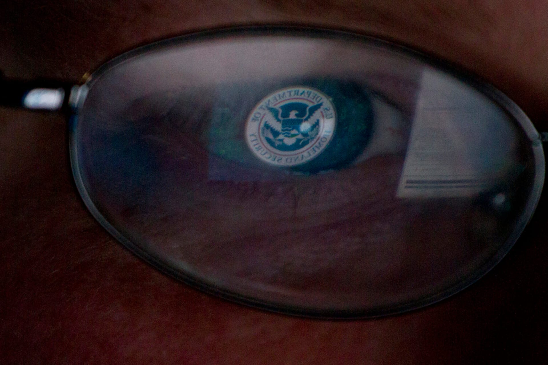 The logo of the U.S. Department of Homeland Security is reflected in the spectacles of an analyst working in a watch and warning center of a cyber security defense lab at the Idaho National Laboratory