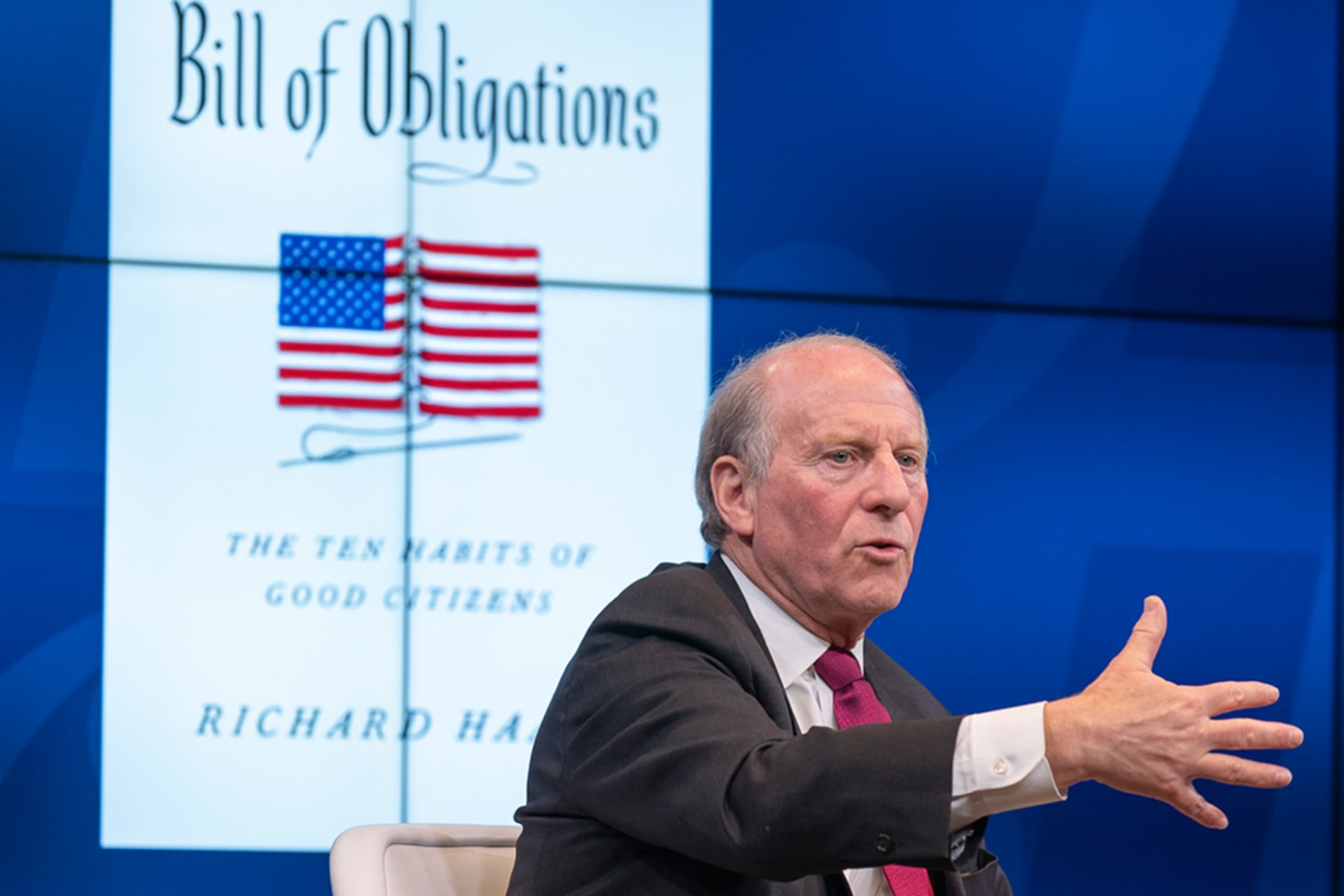 Richard Haass speaks in front of screen showing cover of his new book