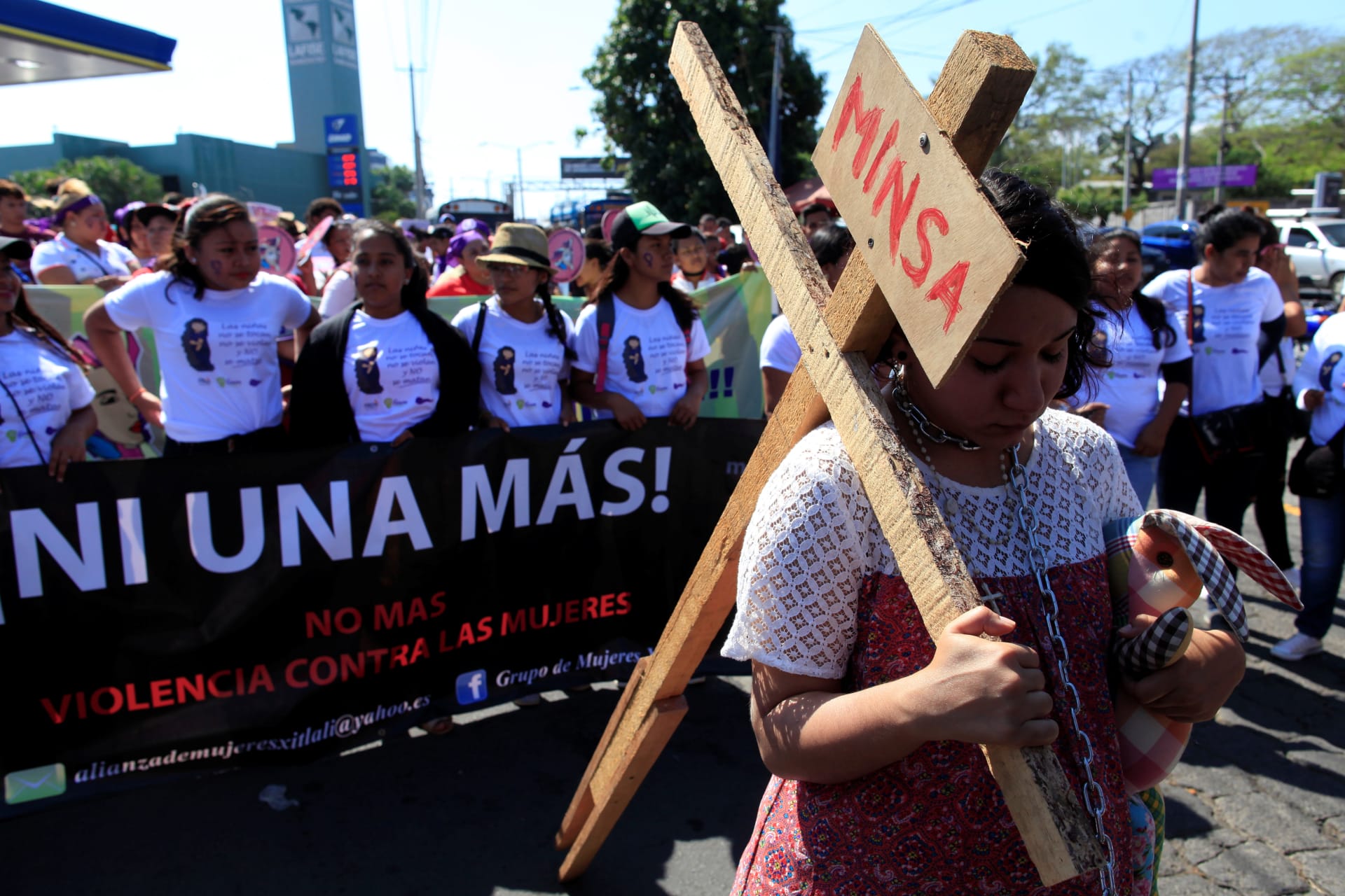An activist carries a cross during a march to mark International Women's Day in Nicaragua on March 8, 2018.The banner reads "Not one more. No more violence against women."