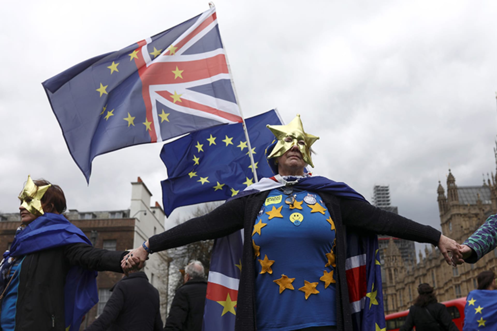 Anti-Brexit protesters wear masks and wave flags during a demonstration in front of the Houses of Parliament in London