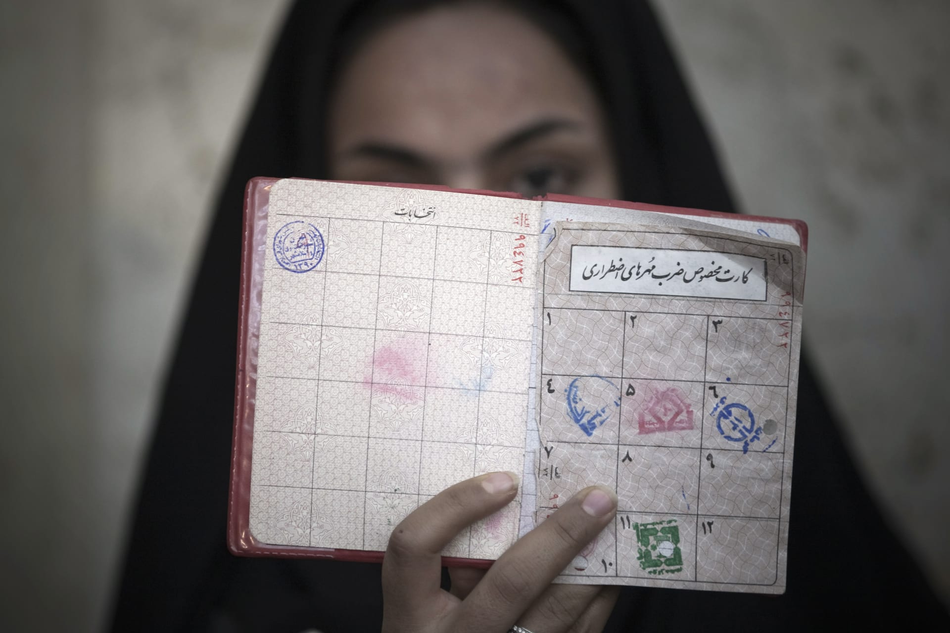 <p>A woman in Iran holds her identification in front of her face after voting March 2, 2012. </p>

