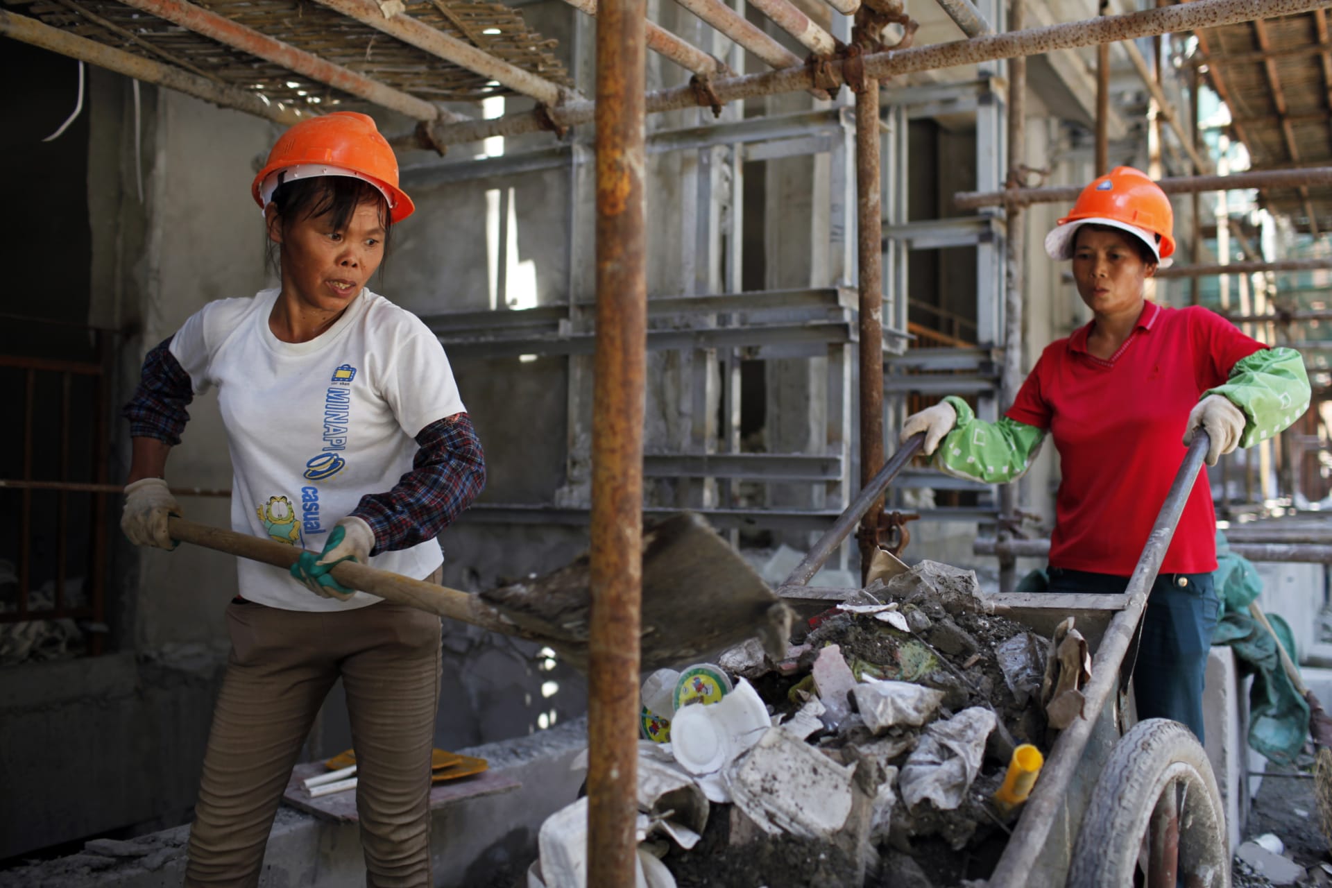 <p>Female migrant construction workers collect garbage onto a cart as they work on a shift at a residential construction site in Shanghai August 12, 2013.</p>
