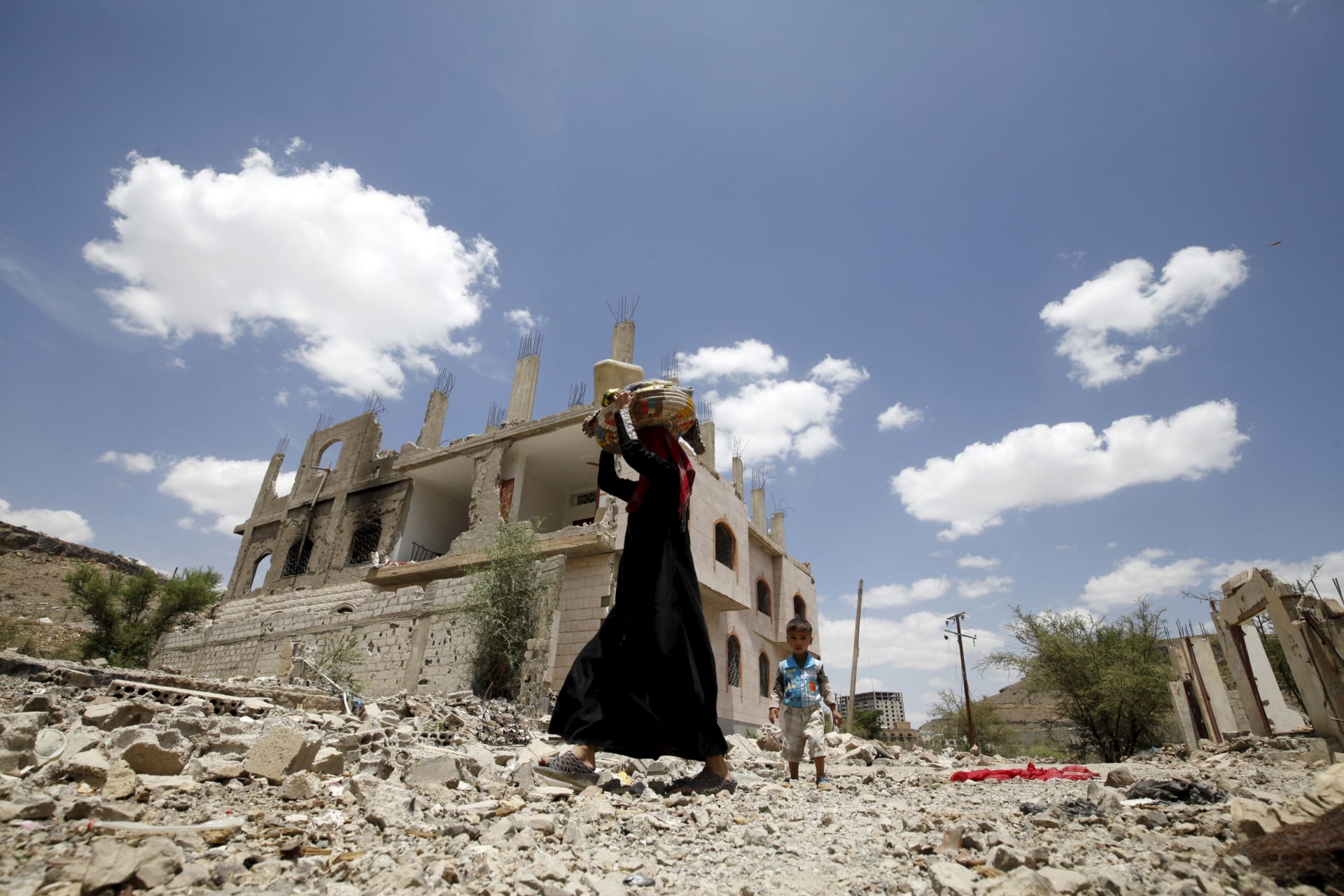 <p>A woman and a boy walk past the ruins of buildings destroyed in Saudi-led air strikes in Yemen’s capital Sanaa. September 13, 2015.</p>
