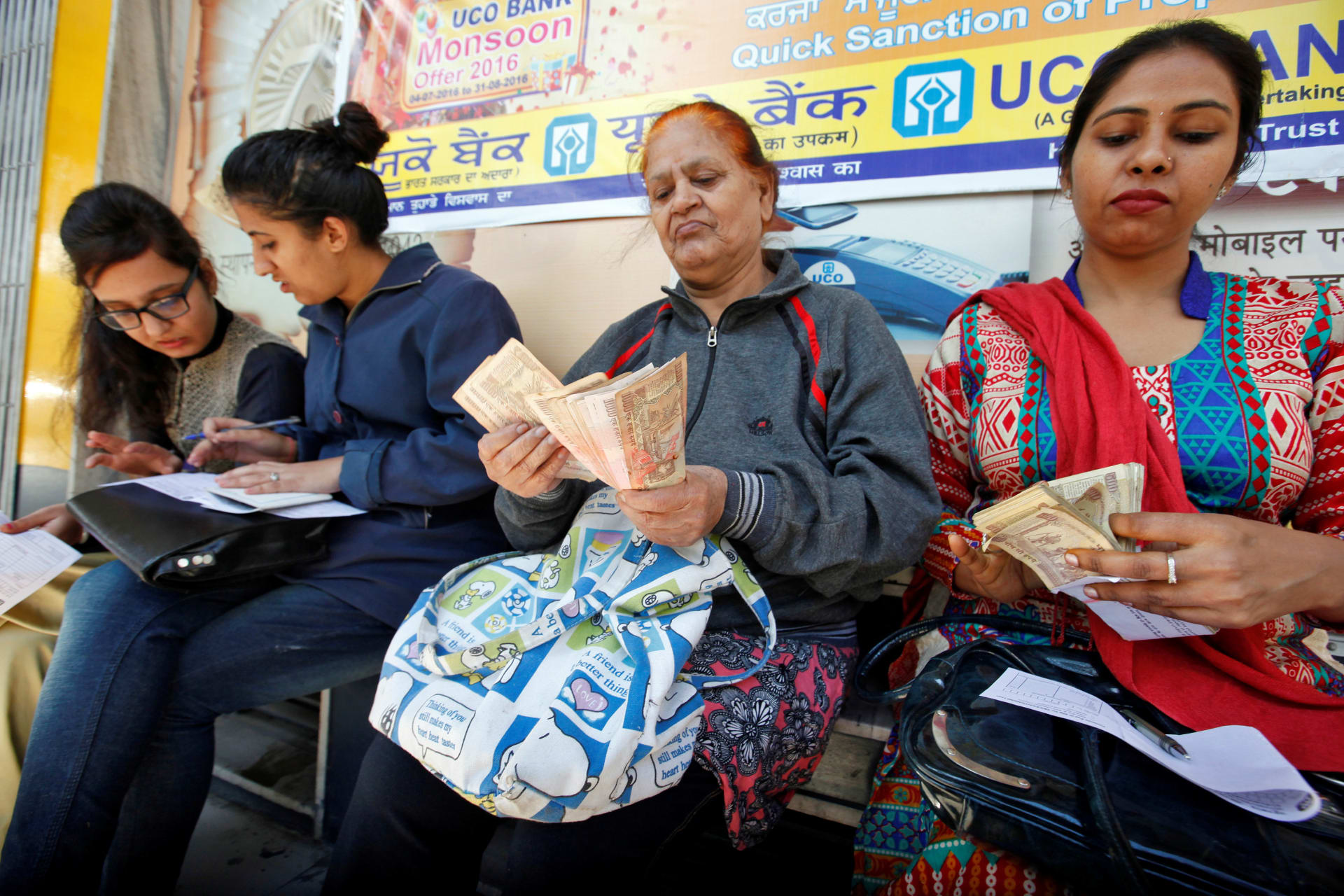 <p>Women count Indian rupee banknotes before depositing them at a bank in Chandigarh, India. November 10, 2016.</p>
