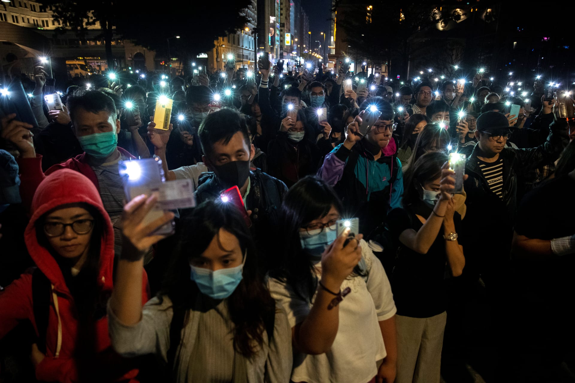 <p>Protesters raise mobile phones as they gather to show support for protesters inside the Hong Kong Polytechnic University (PolyU) campus, November 19, 2019</p>
