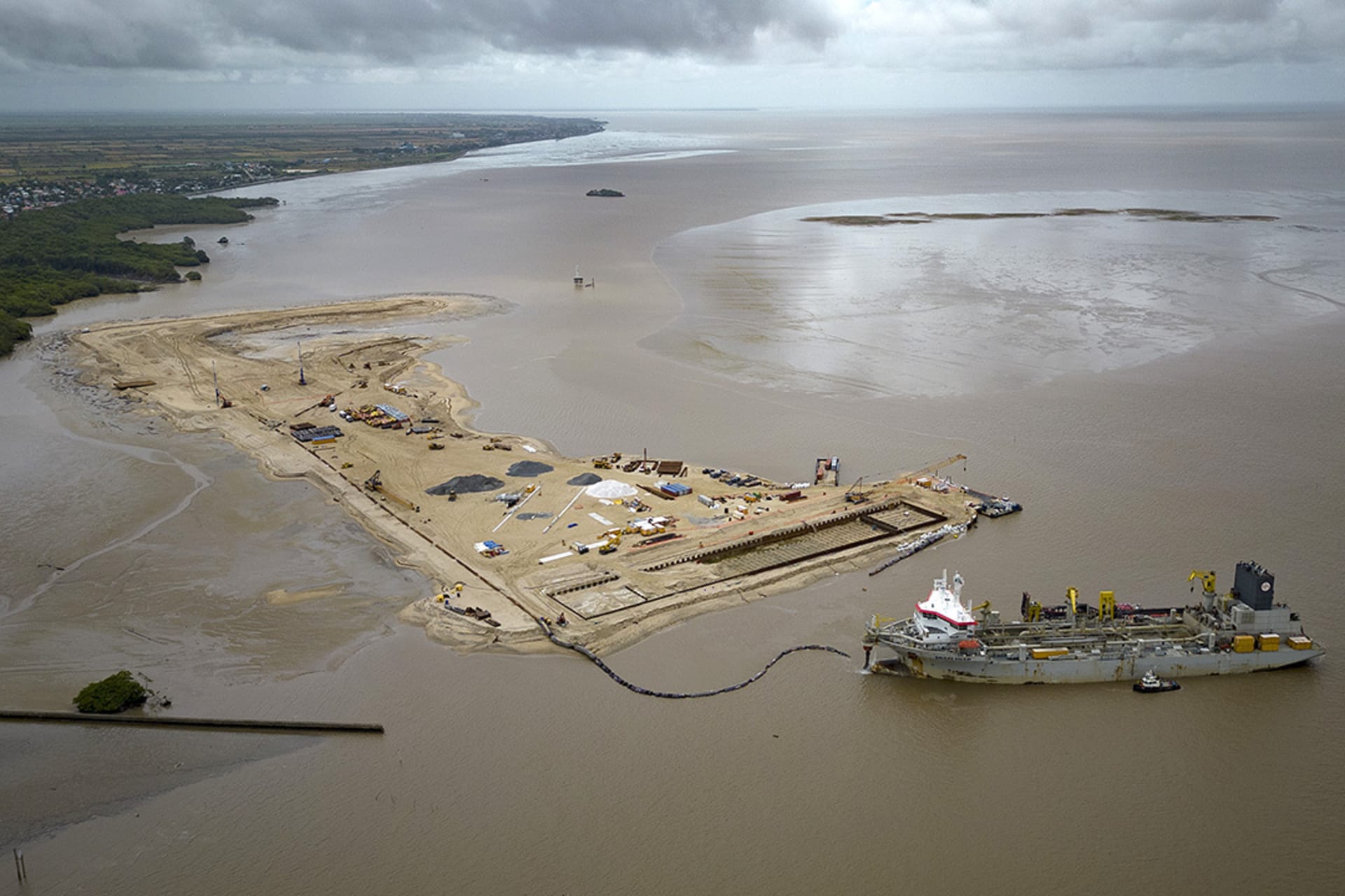 <p>A ship creates an artificial island for a coastal port for offshore oil production at the mouth of the Demerara River in Georgetown, Guyana, April 12, 2023.</p>
