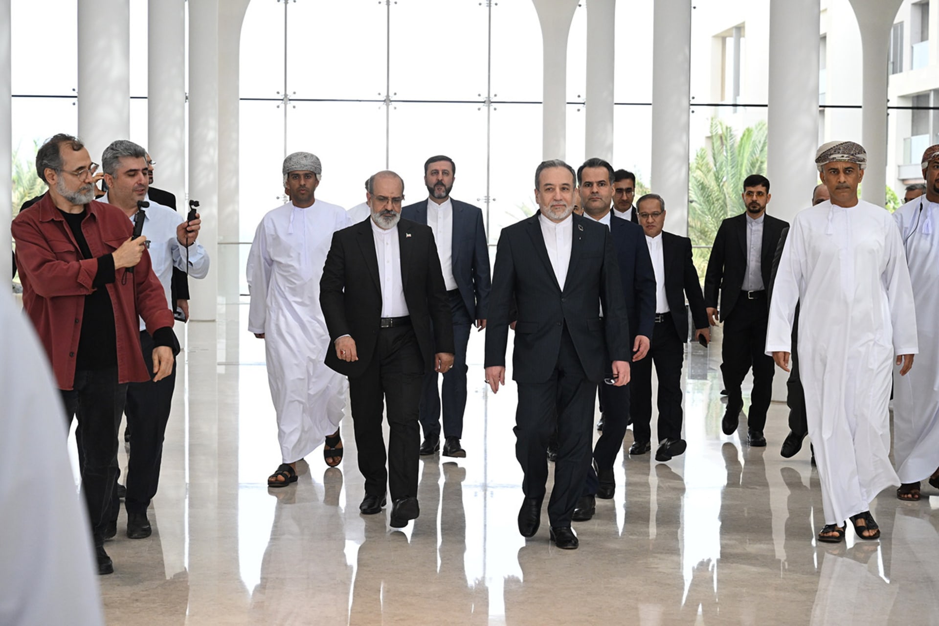 Iranian negotiators walk in formal attire down a hallway.