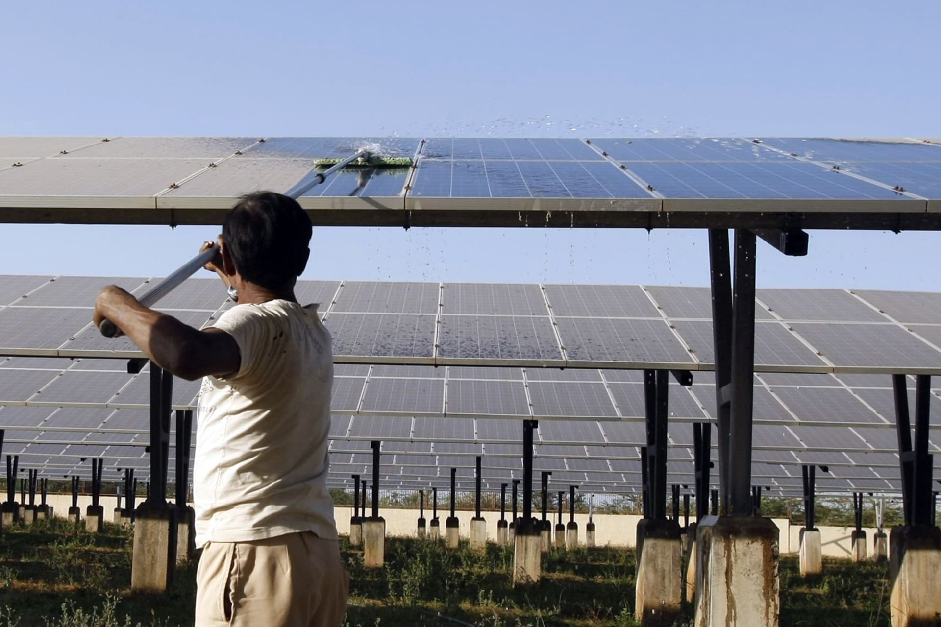 A worker cleans photovoltaic solar panels inside a solar power plant at Raisan village near Gandhinagar, in the western Indian state of Gujarat
