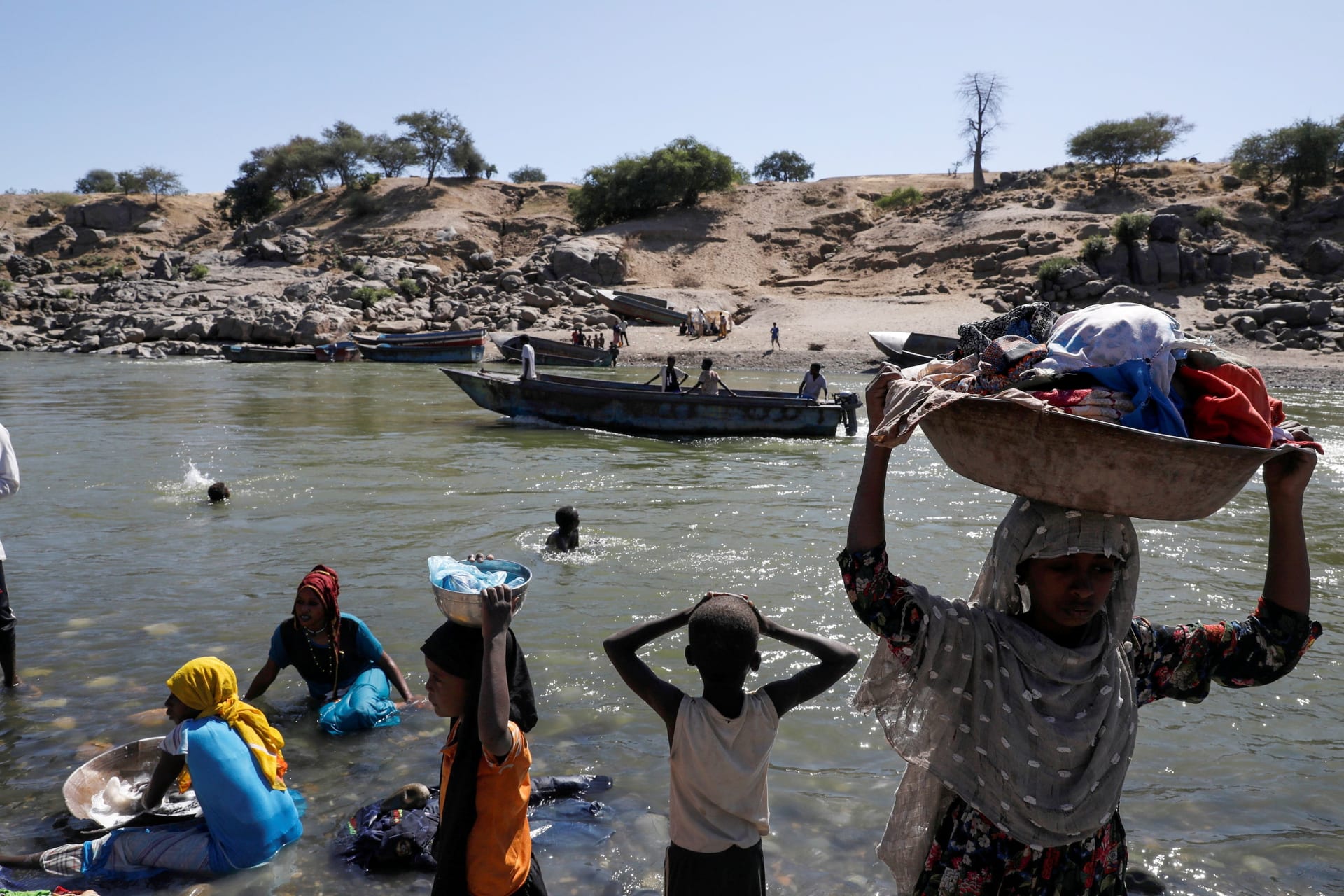<p>Refugees stand on the Ethiopian bank of a river that separates Sudan from Ethiopia near the Hamdeyat refugees transit camp, which houses Ethiopian refugees fleeing the fighting in the Tigray region, on the Sudan-Ethiopia border, Sudan, November 30, 2020.</p>

