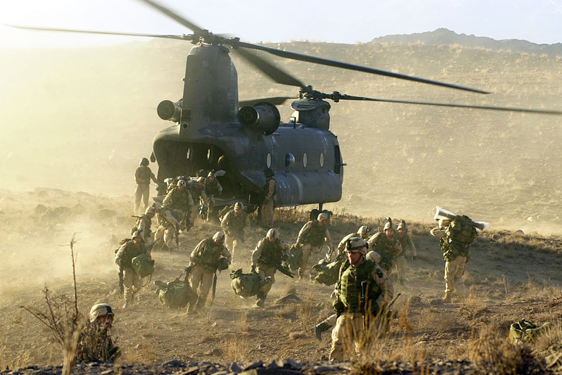A photo of U.S. soldiers exiting a helicopter in the dessert landscape of Afghanistan.
