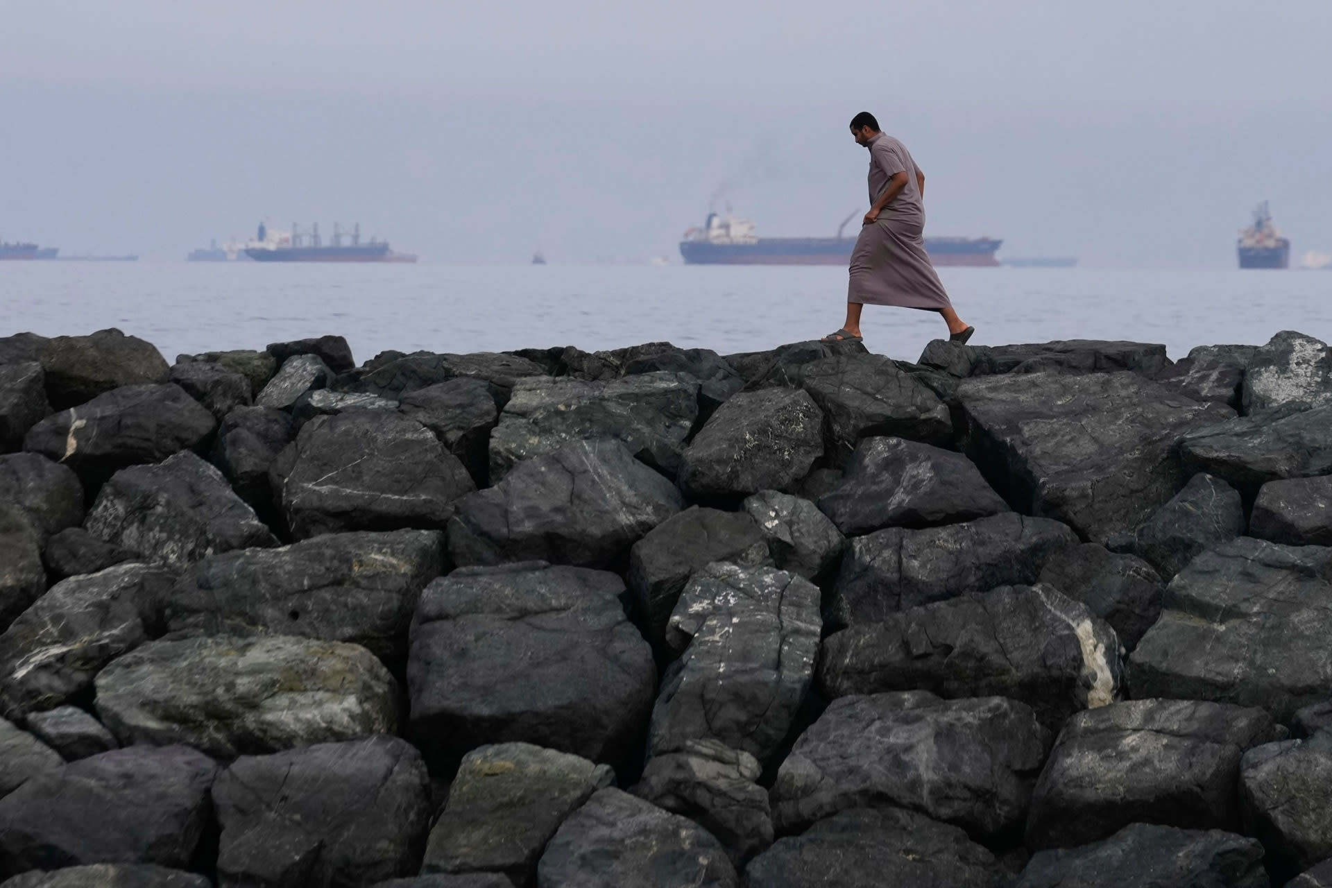<p>A man walks along the shore as oil tankers and cargo ships line up in the Strait of Hormuz, seen from Khor Fakkan, United Arab Emirates, Wednesday, March 11, 2026.</p>
