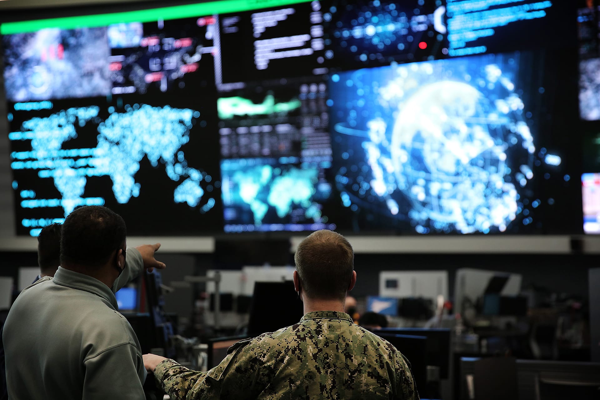 Two officials at U.S. Cyber Command, headquartered in Fort George G. Meade, Maryland, examine a row of screens at their workplace. 