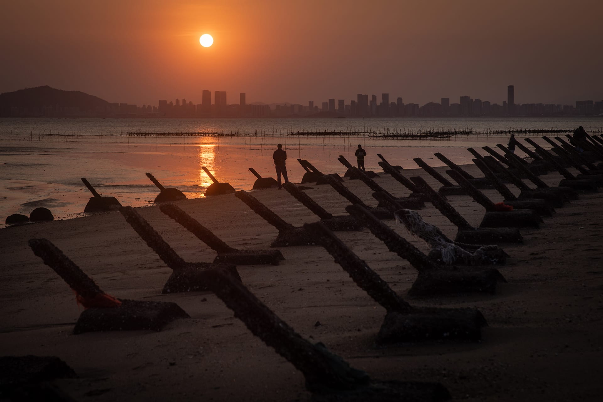 Anti-tank fortifications on beach at sunset.