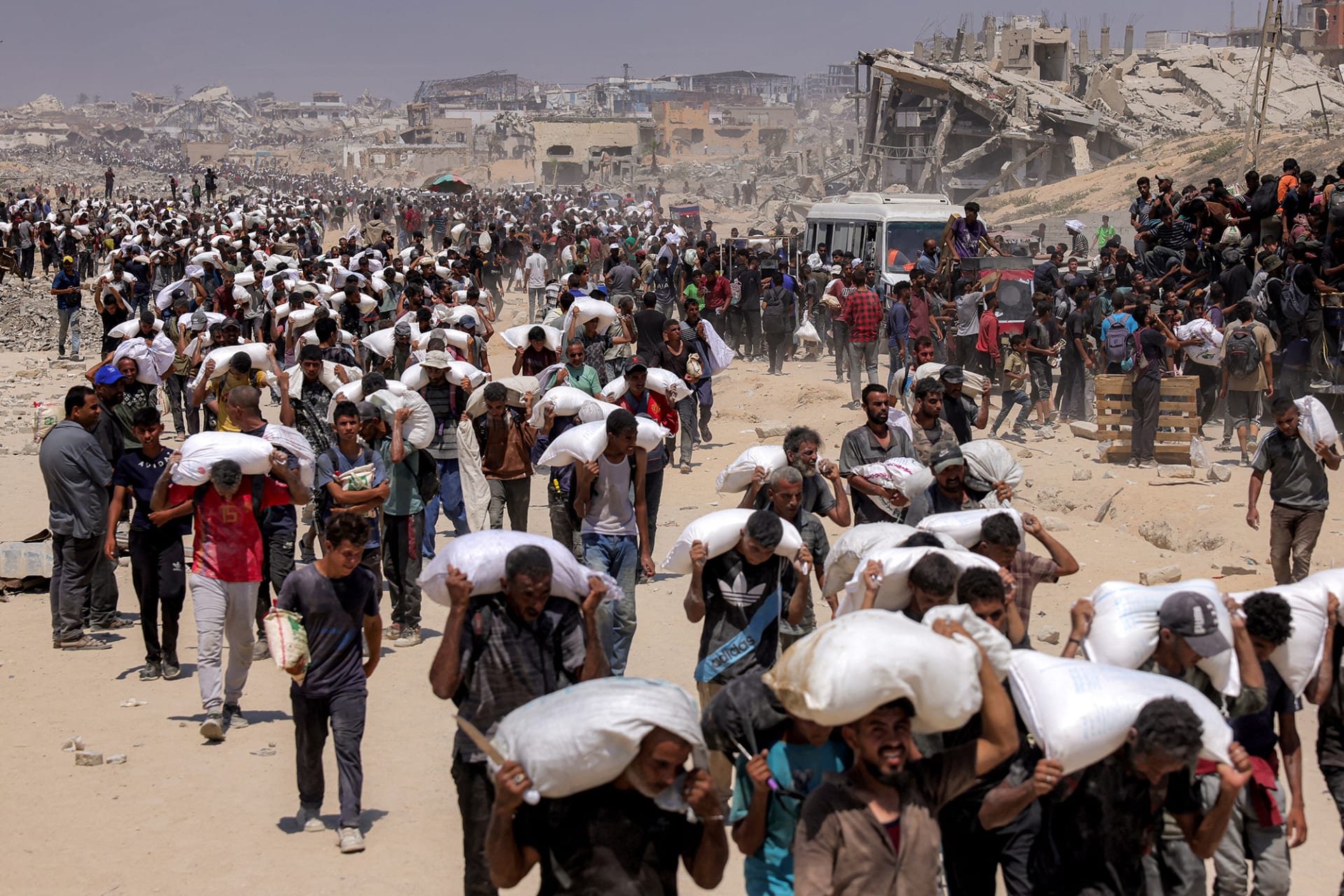 People walk with sacks of flour delivered after trucks carrying humanitarian aid entered northern Gaza on July 27, 2025 coming from the Zikim border crossing.