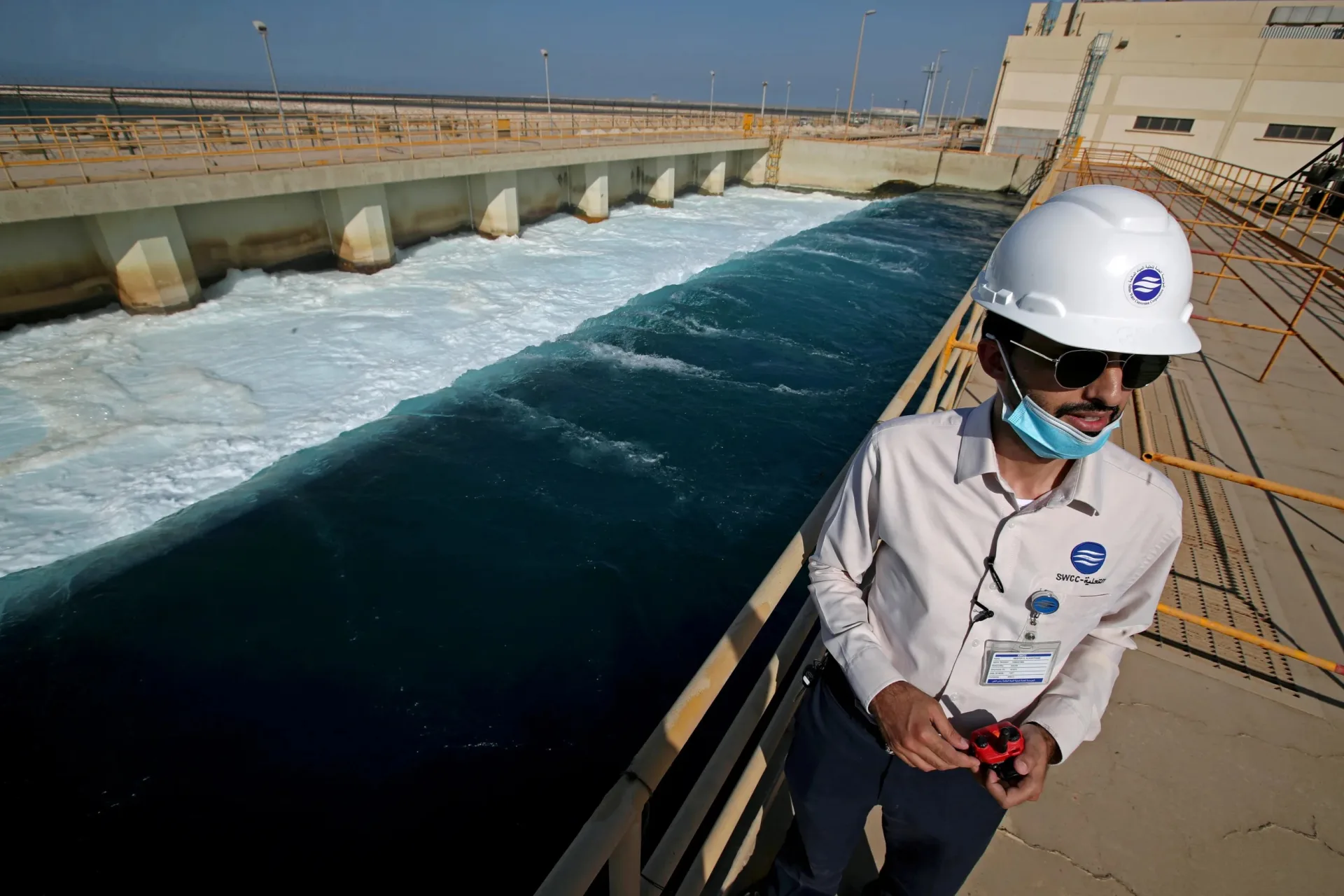 An employee stands next to a waste water collection pool, at the Saline Water Conversion Corporation's Ras Al-Khair Power and Desalination Plant, in Ras Al-Khair, Saudi Arabia, on October 8, 2020.