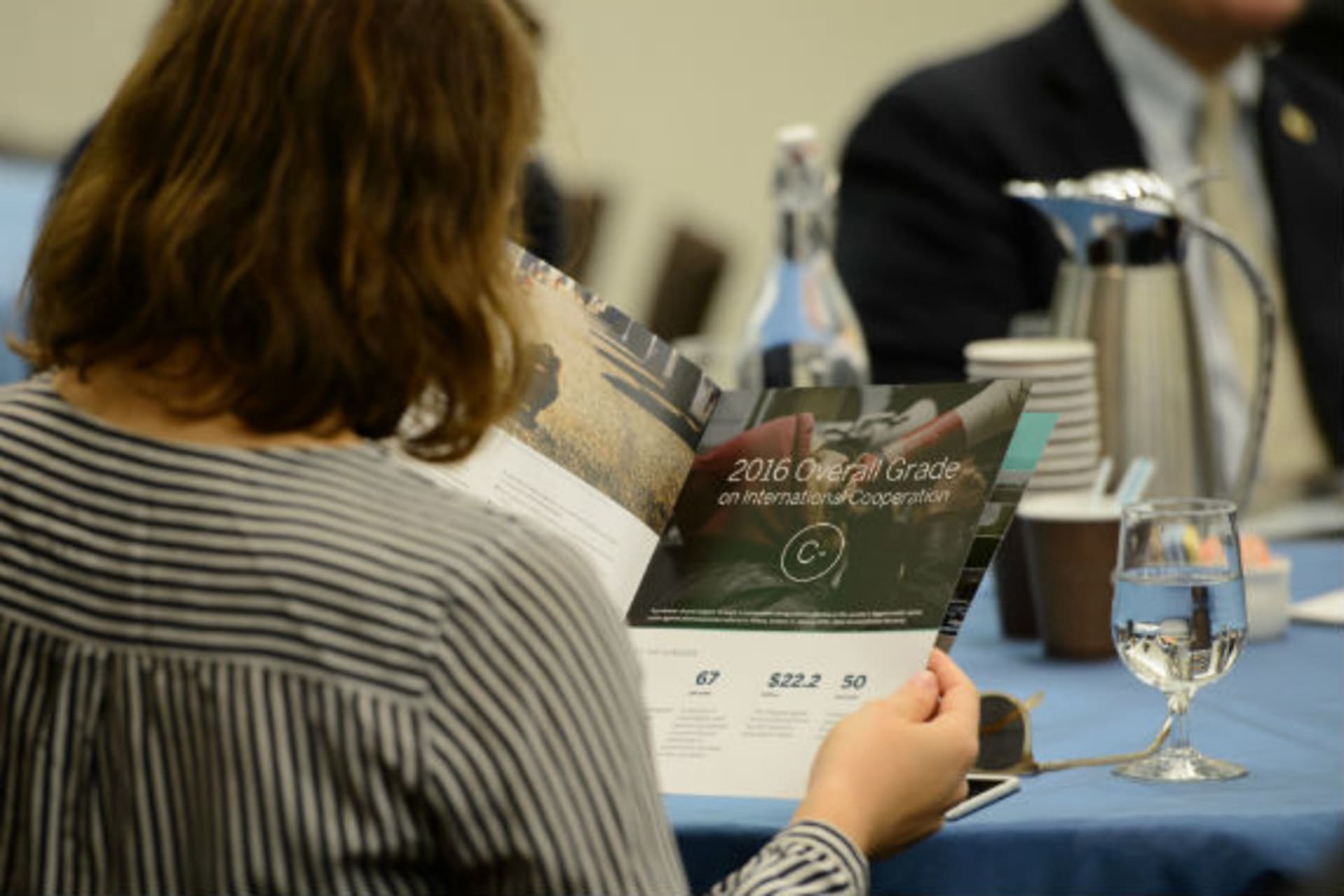 <p>A participant reads the Council of Councils 2016 Report Card on International Cooperation. (Kaveh Sardari)</p>
