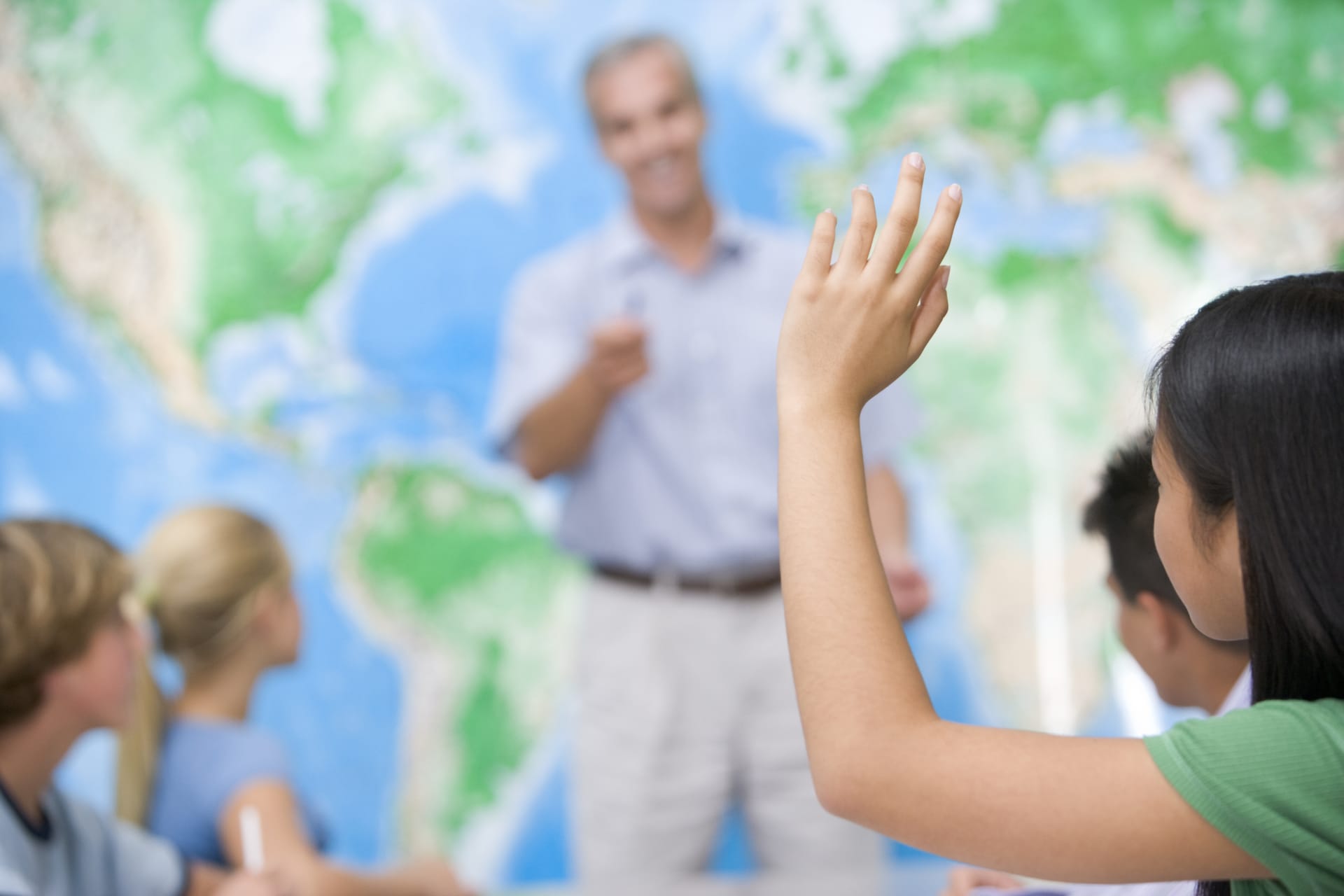 teacher calling on students with a map behind them