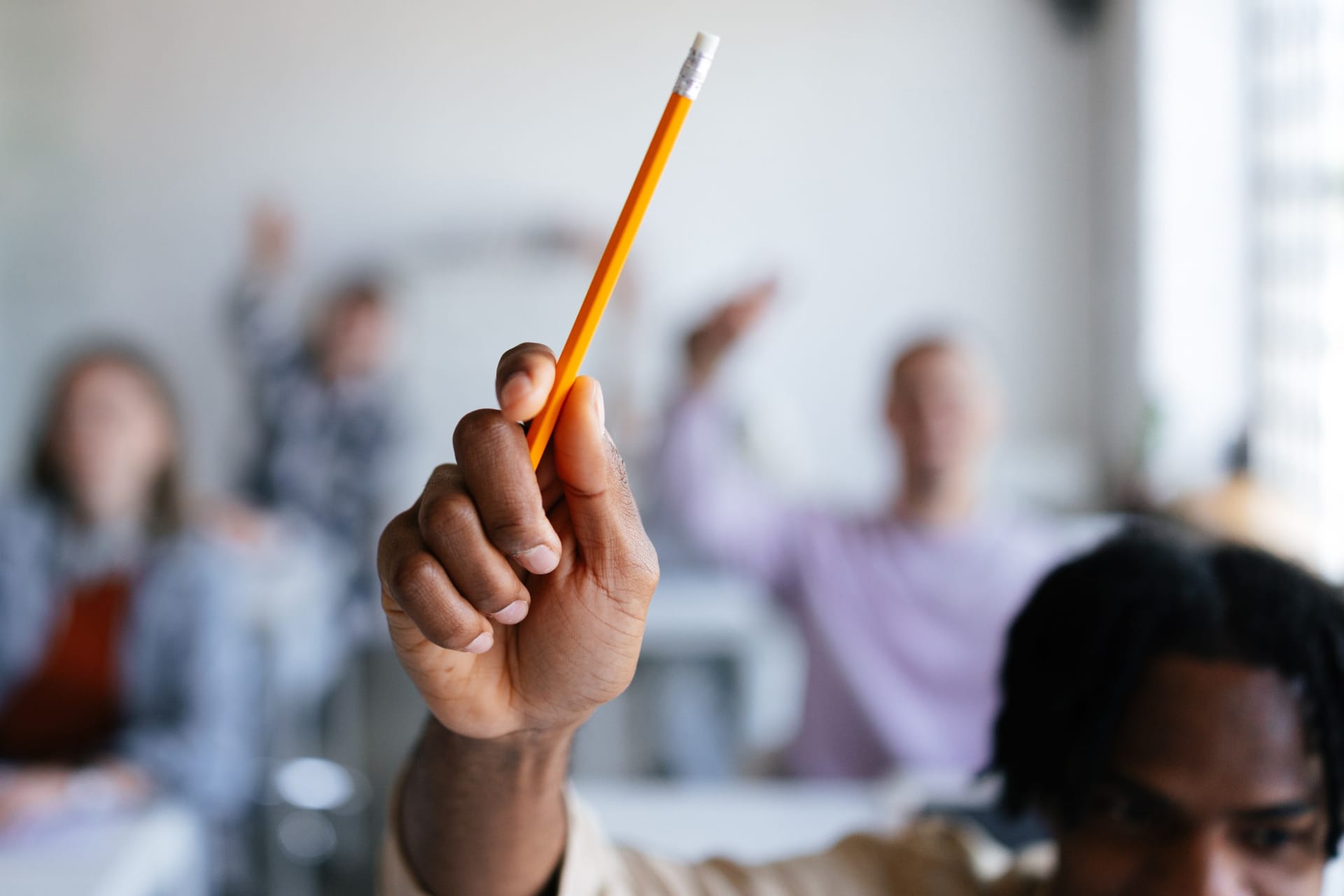 student raising hand with pencil