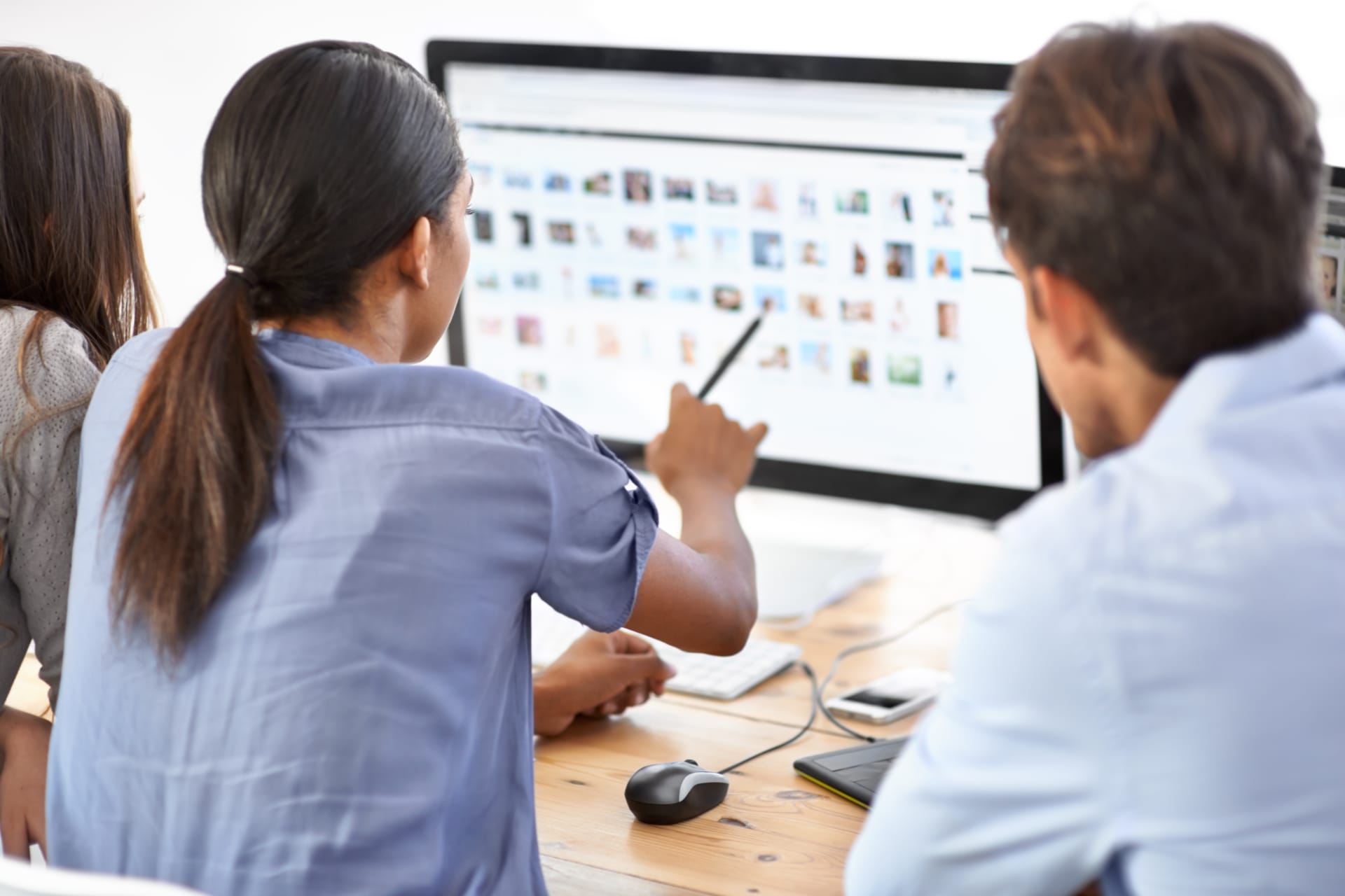 A woman pointing at files on a desktop computer screen and a man watching intently