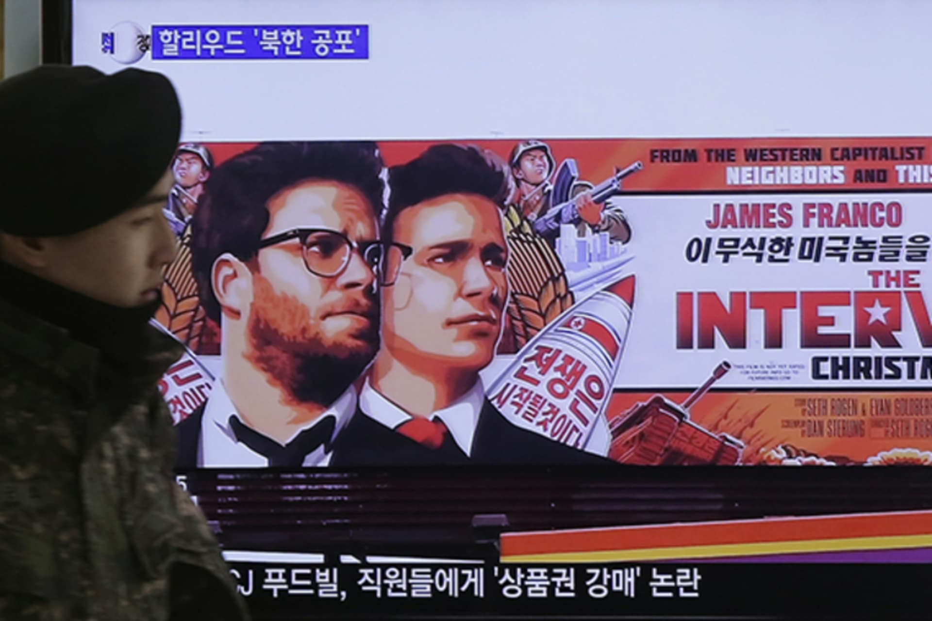 A South Korean army soldier walks near a TV screen showing an advertisement of Sony Pictures' The Interview in Seoul, South Korea, on December 22, 2014.