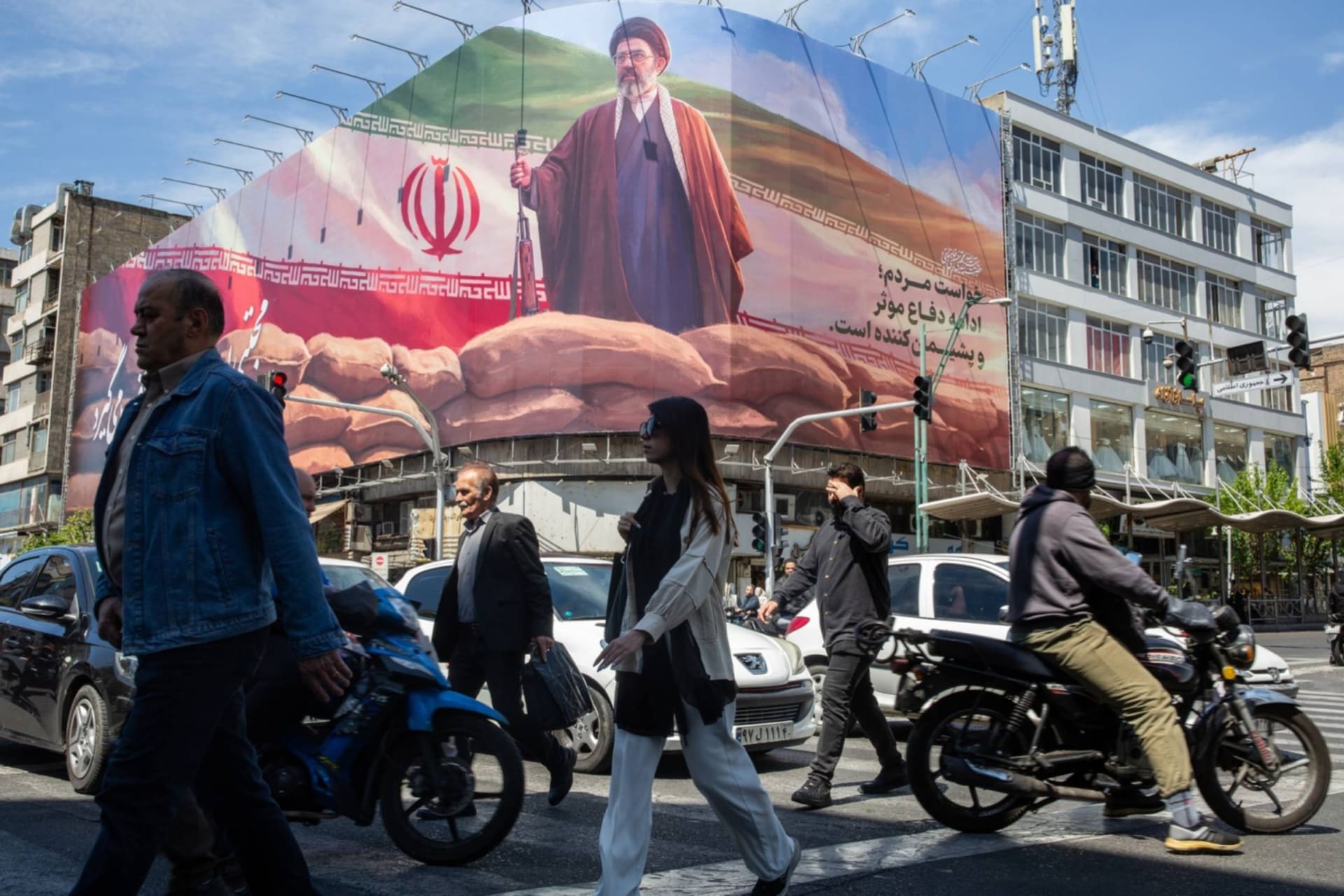 Pedestrians cross Enghelab Square, near a billboard showing Mojtaba Khamenei, the new supreme leader, in Tehran,  April 11, 2026. (Arash Khamooshi/The New York Times)