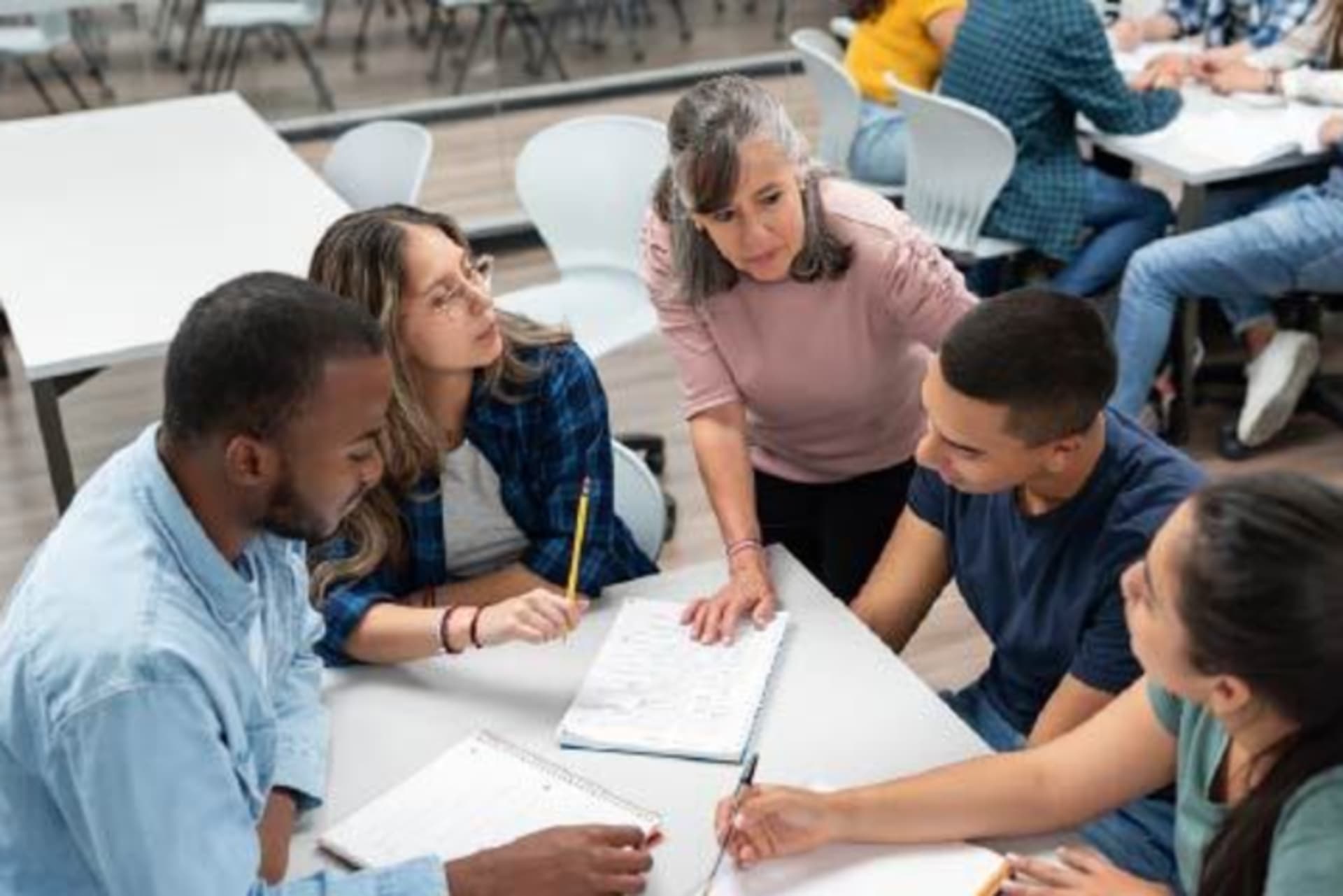 Teacher sitting with students around a table