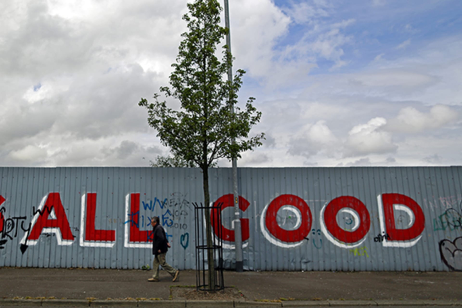A man walks past graffiti on a section of a peace wall near the Shankill Road in West Belfast