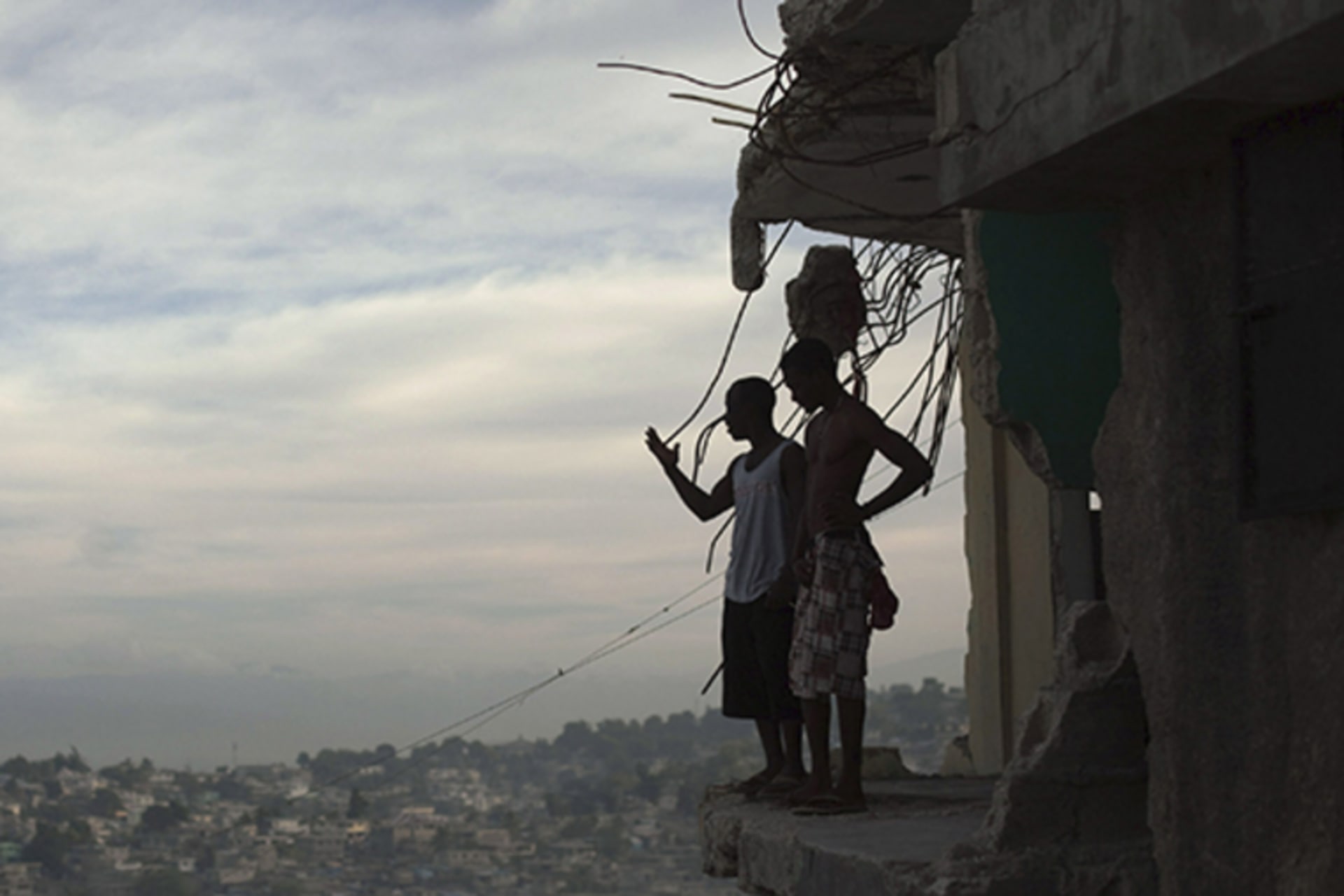 Two men stand on the edge of their partially destroyed apartment in Port-au-Prince, Haiti, on January 9, 2011, almost one year after the earthquake that killed around 250,000 people and wrecked much of the capital.