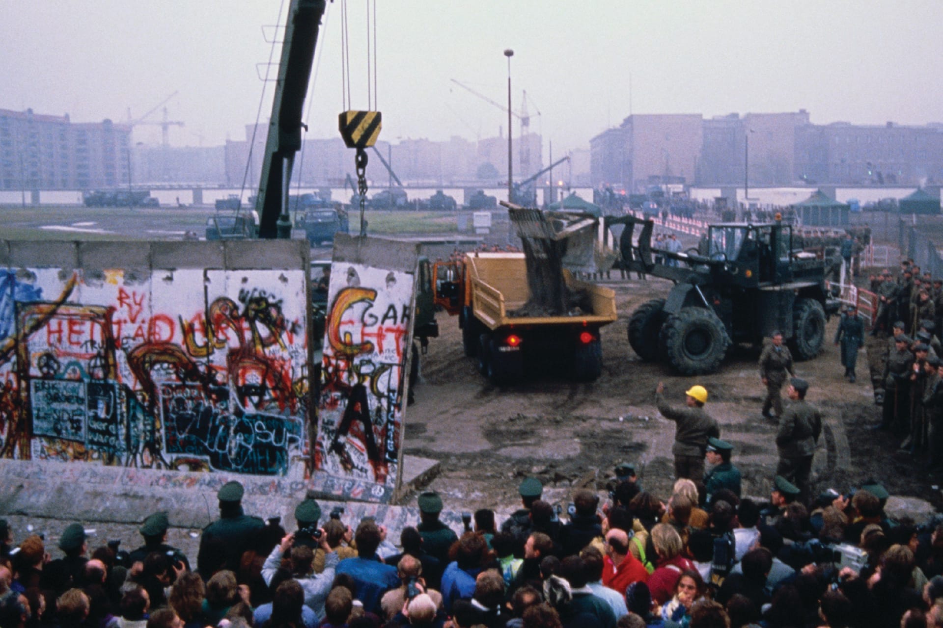Crowd watches as workmen deconstruct the Berlin Wall in Germany in late 1989.