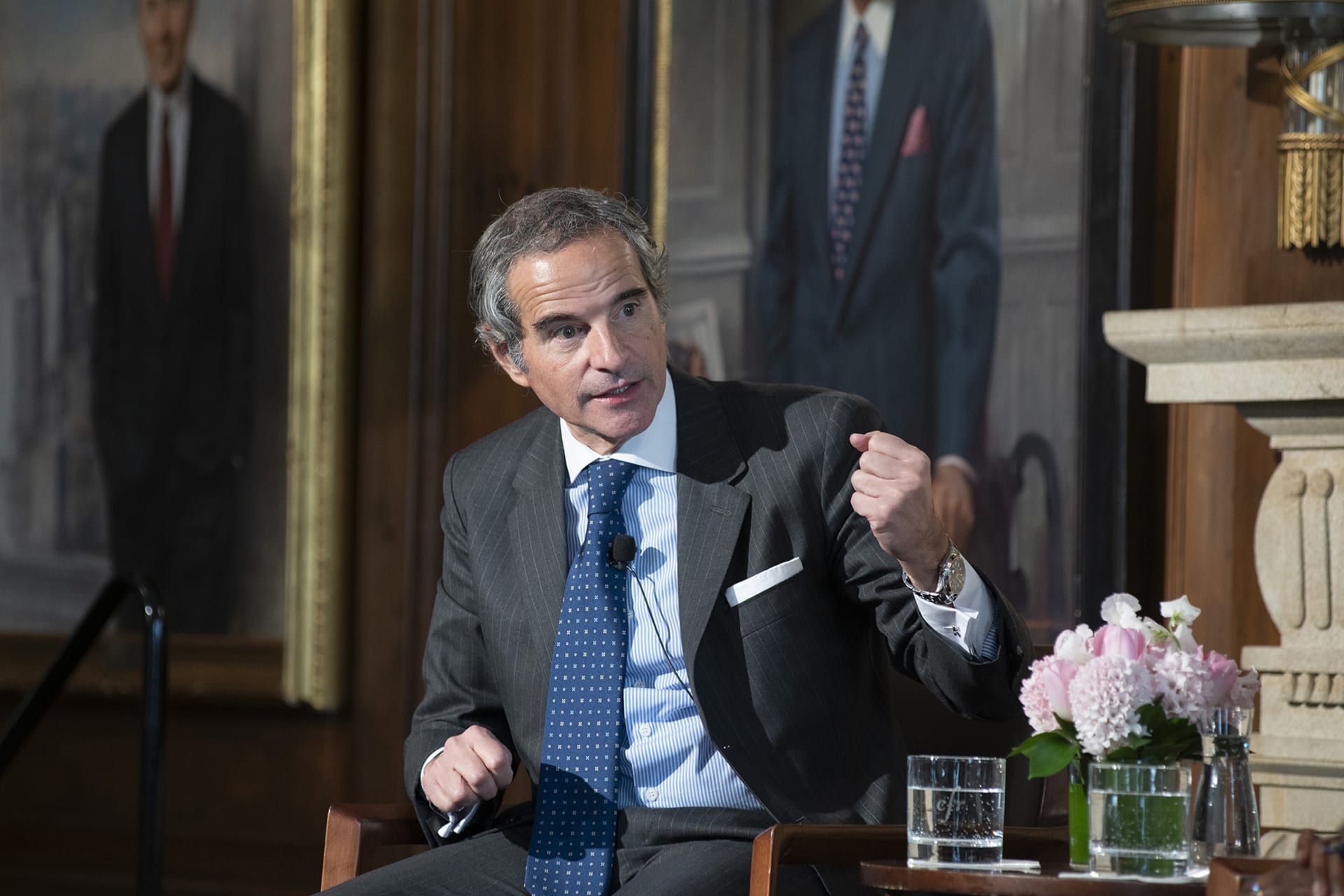 Rafael Grossi sits in a chair, making a hand gesture while speaking during an event.